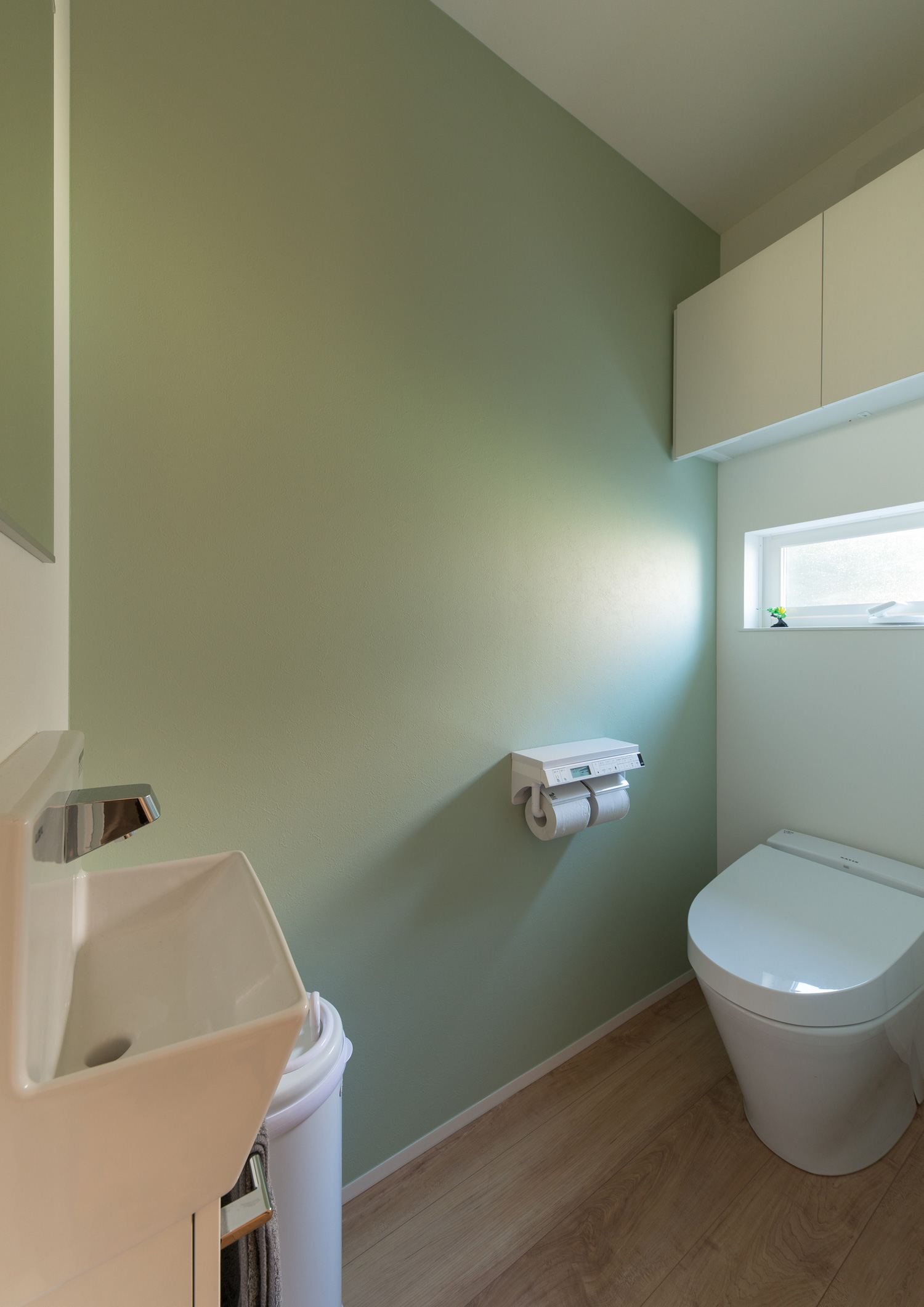 グリーンのアクセントクロスを設けた手洗いカウンターのあるトイレ・デザイン住宅