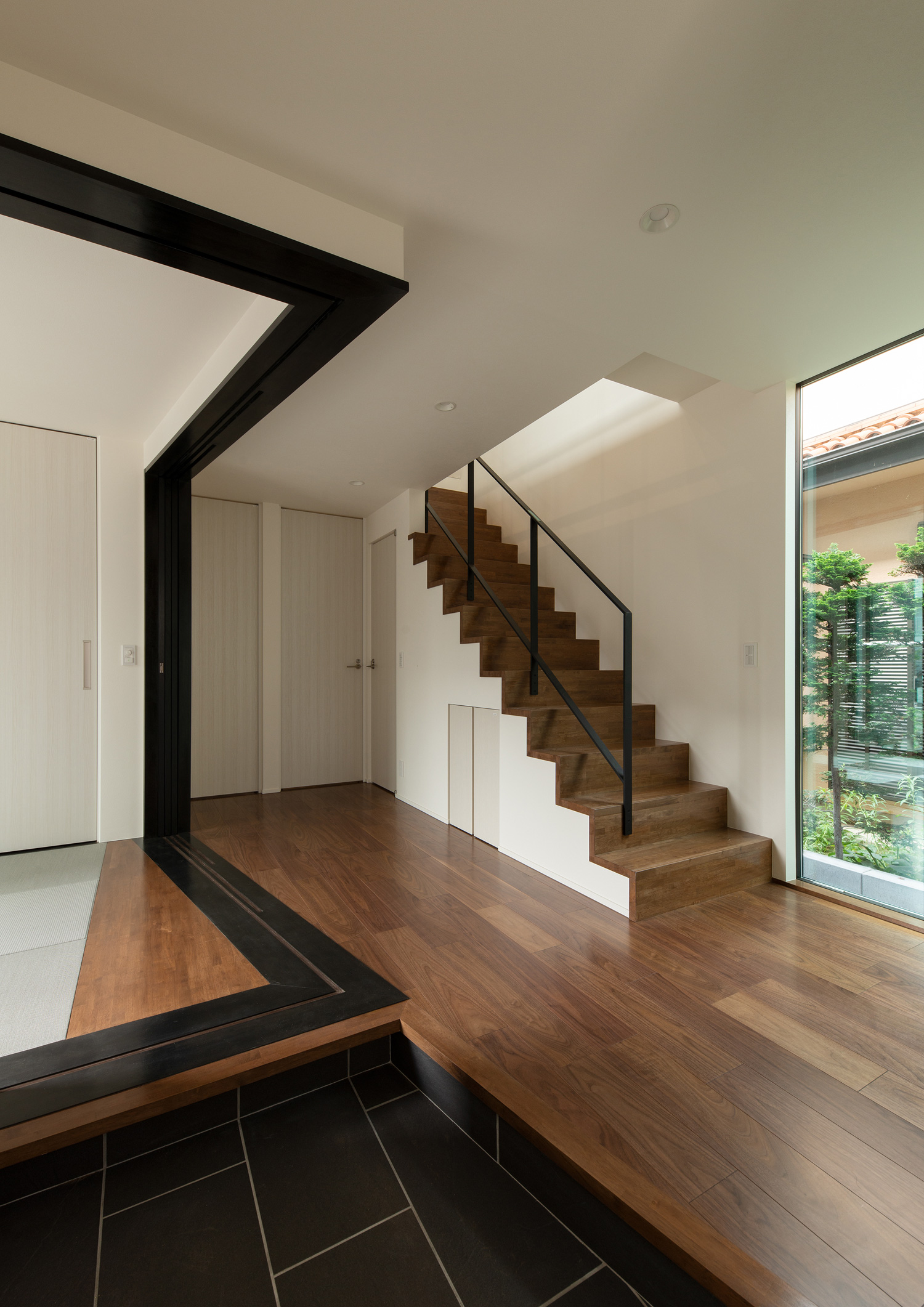 木製の箱型階段のあるフロアと和室の両方にアクセスできる玄関・デザイン住宅