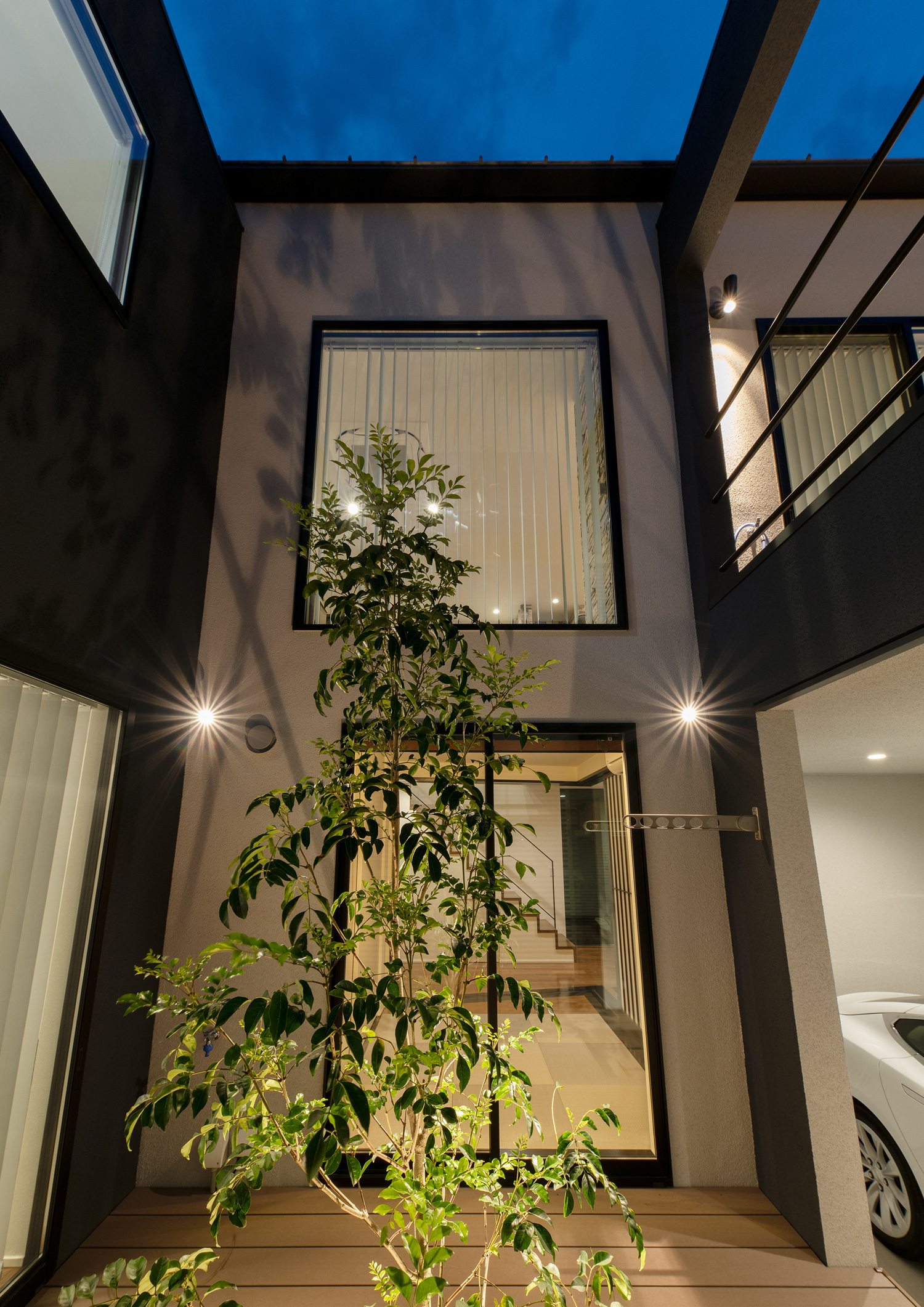 照明に照らされたシンボルツリーがある中庭から上を見上げた様子・デザイン住宅