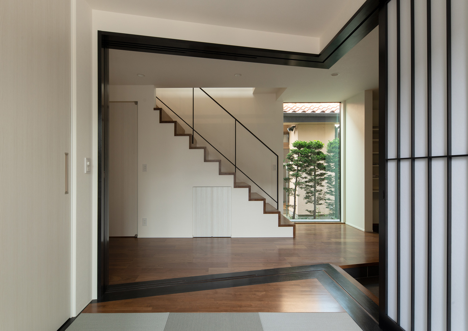 箱型階段のある廊下と黒枠の障子で仕切られた和室・デザイン住宅