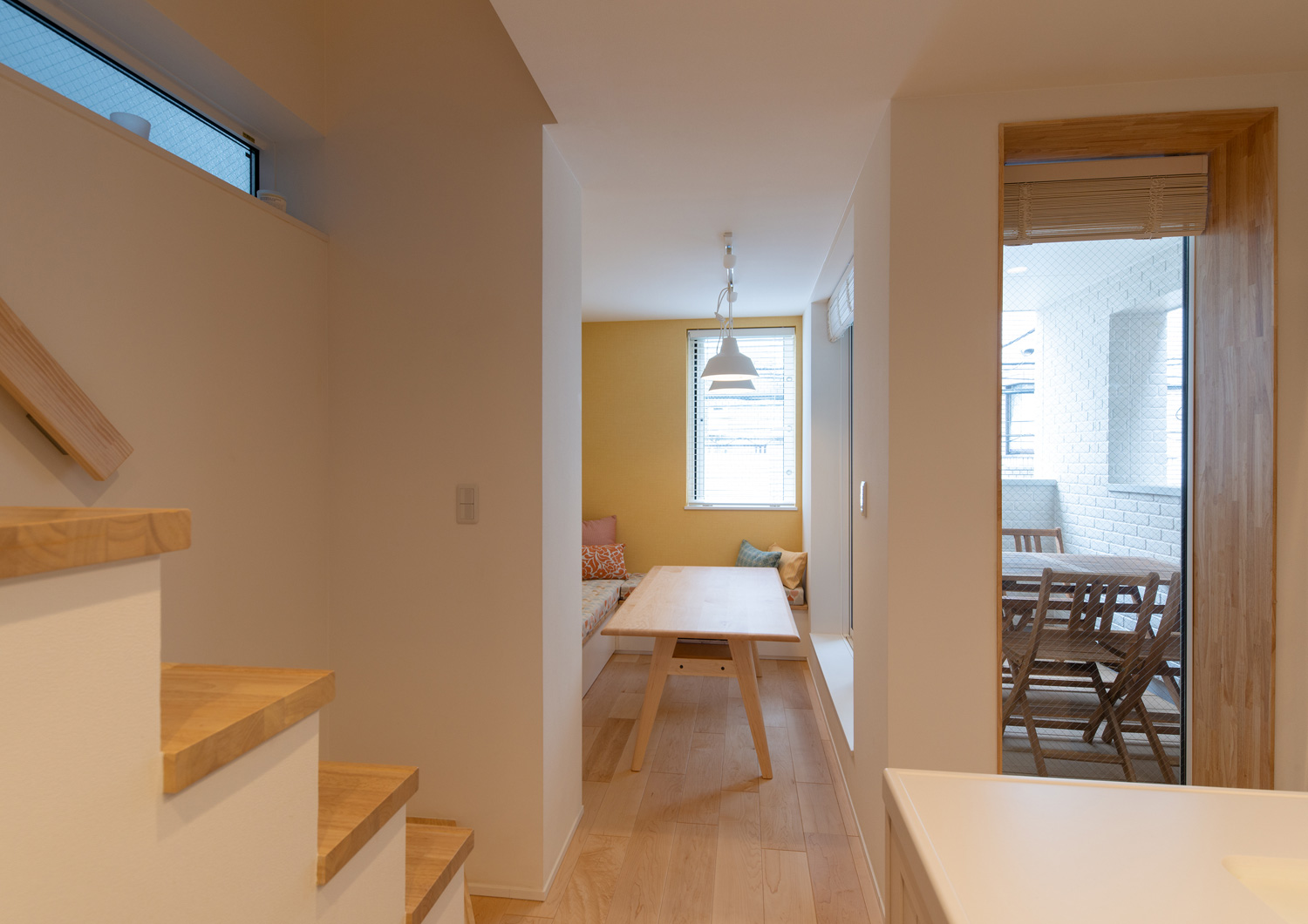 黄色のクロスの空間に造作ベンチや木のテーブルがある様子・デザイン住宅