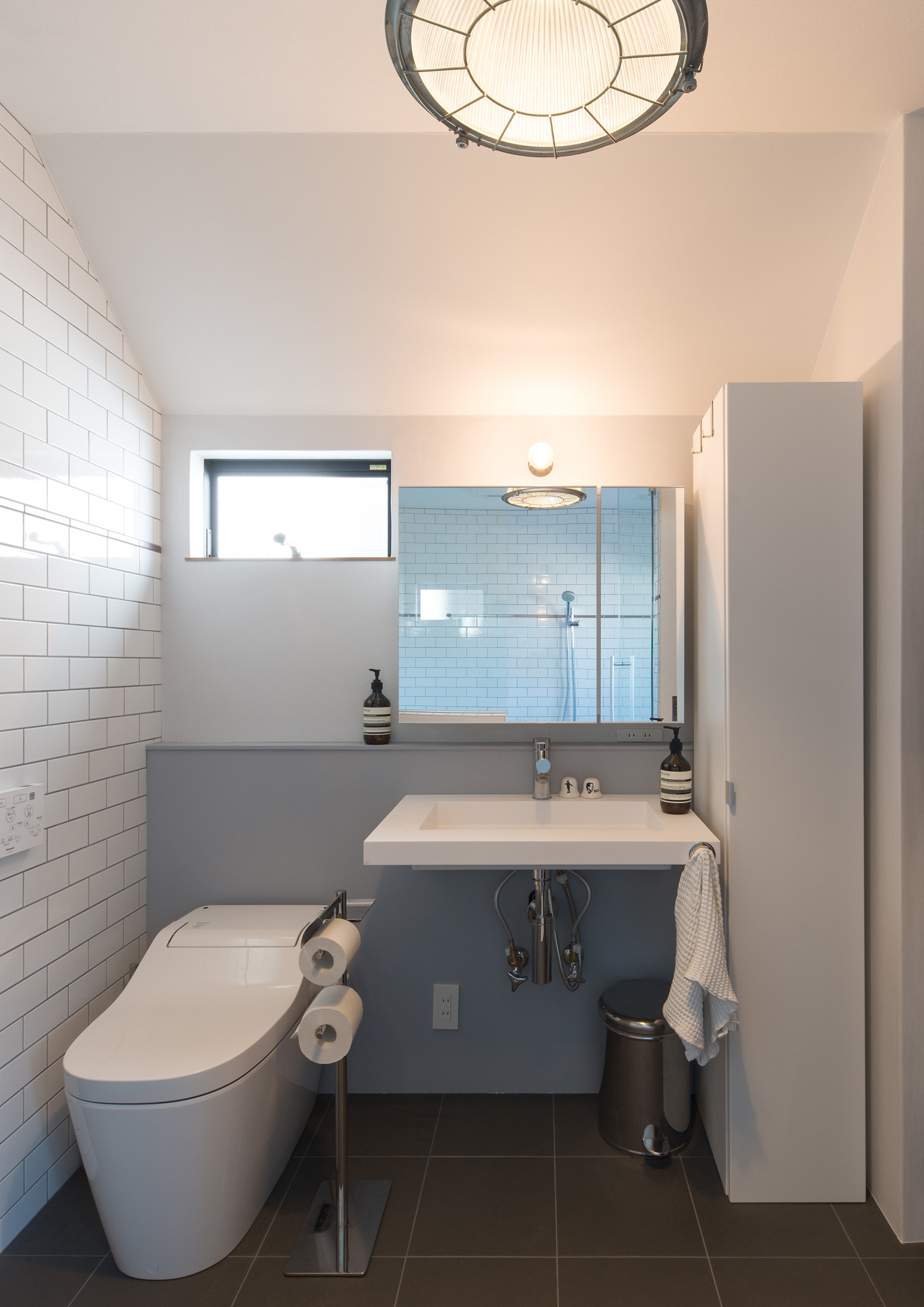 トイレと洗面台が並んだタイルの壁の空間・デザイン住宅
