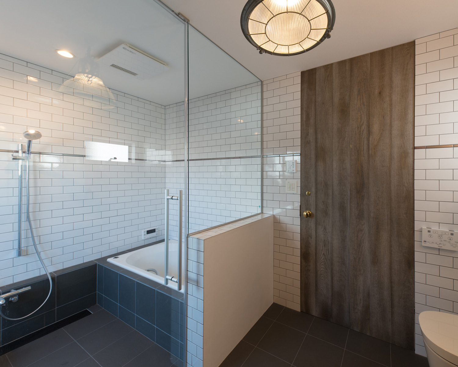 浴室と洗面所が同じタイルの壁で、ガラスで仕切られている様子・デザイン住宅