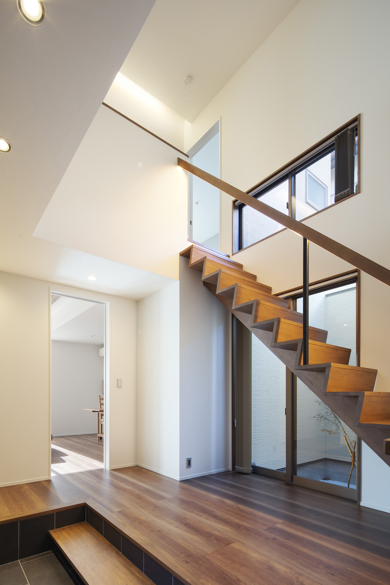 白い壁の空間に、木製のスケルトン階段がある様子・デザイン住宅
