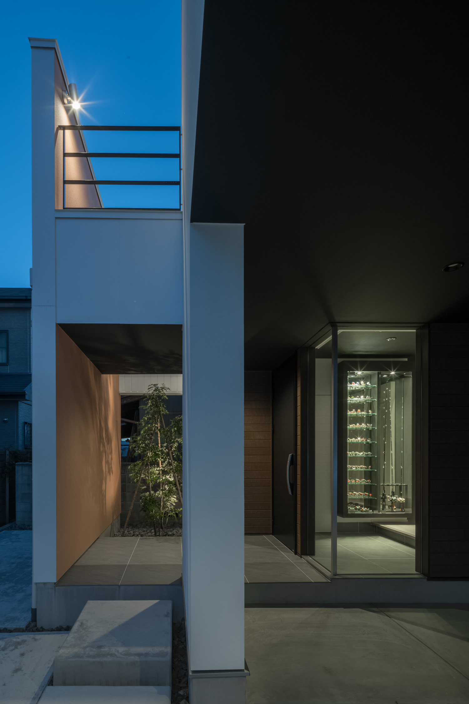 壁で仕切られたアプローチとインナーガレージが玄関ポーチで合流する様子・デザイン住宅
