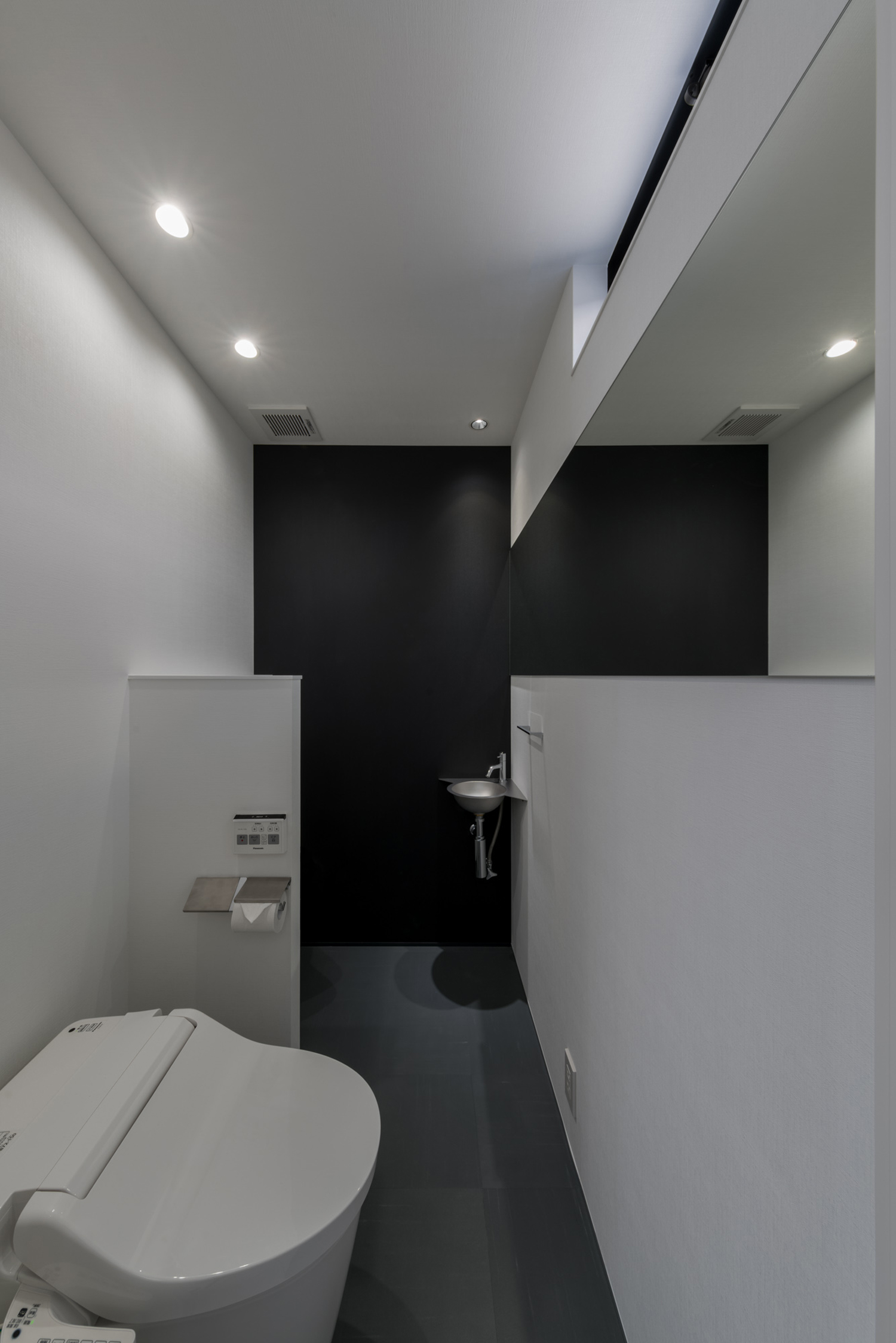 黒いアクセントクロスや、ステンレスの薄型手洗いがあるトイレ・デザイン住宅