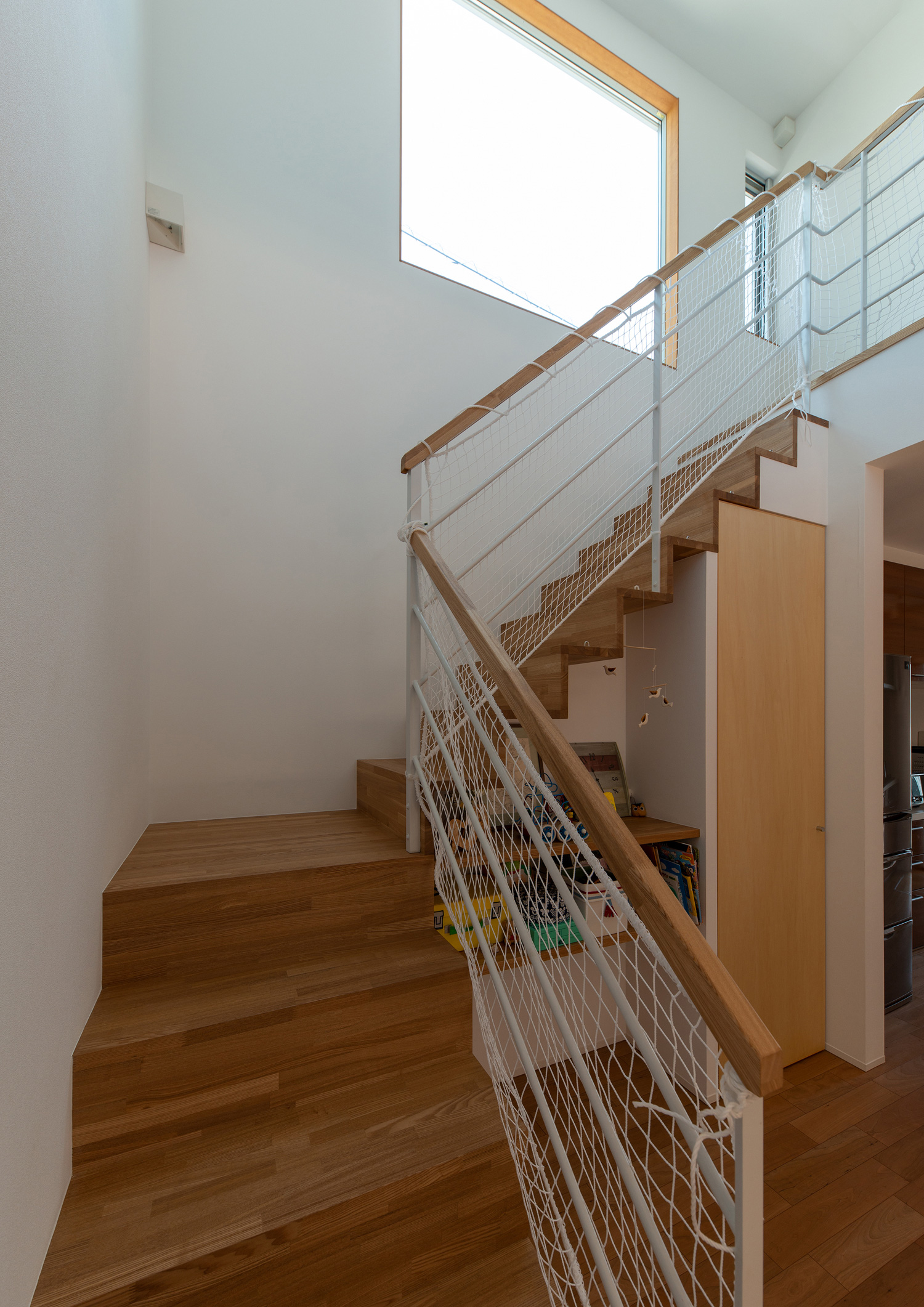 木製の階段がある壁に窓が設けられた様子・デザイン住宅