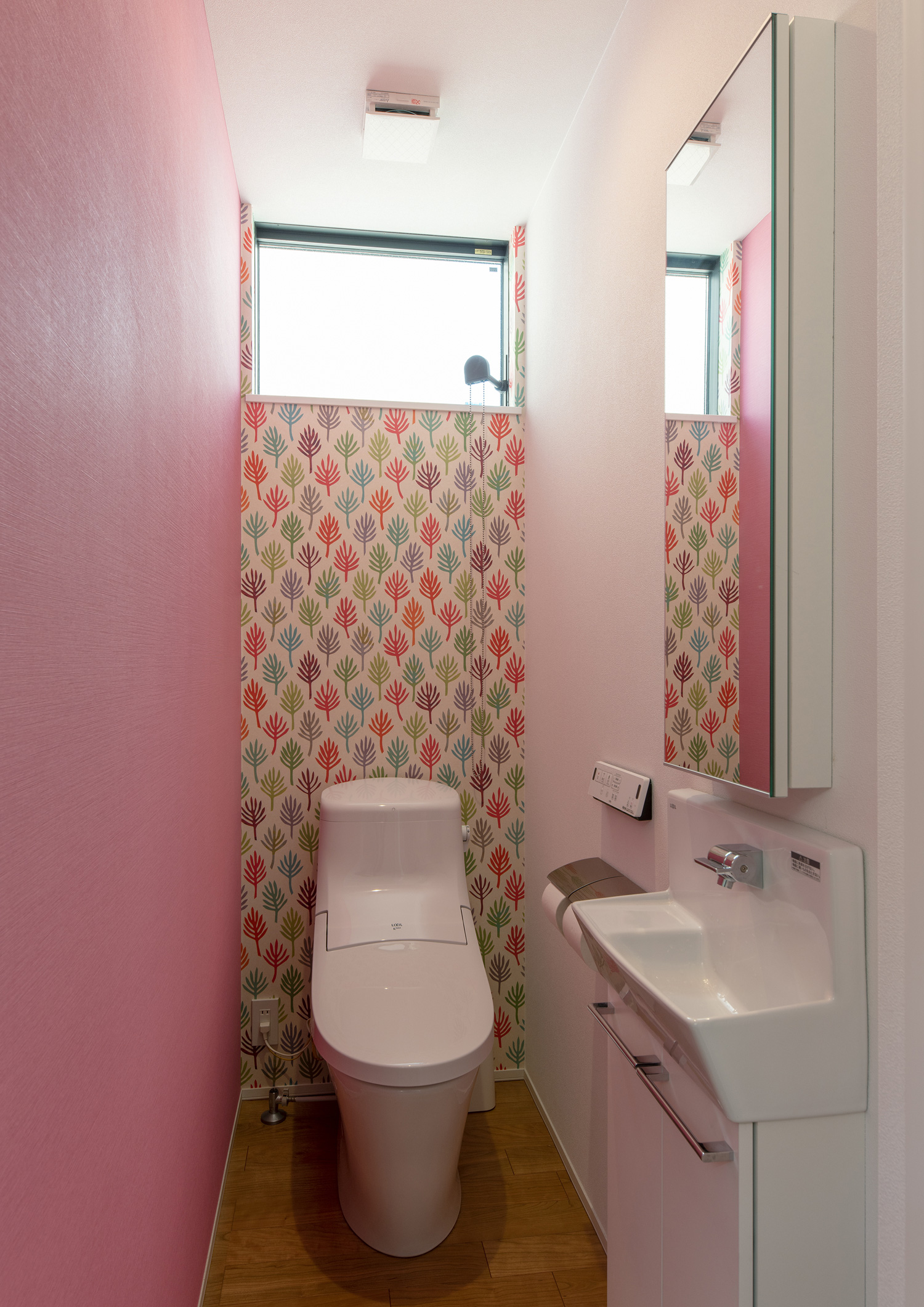 ピンク色のクロスと柄のクロスを設けたトイレ・デザイン住宅