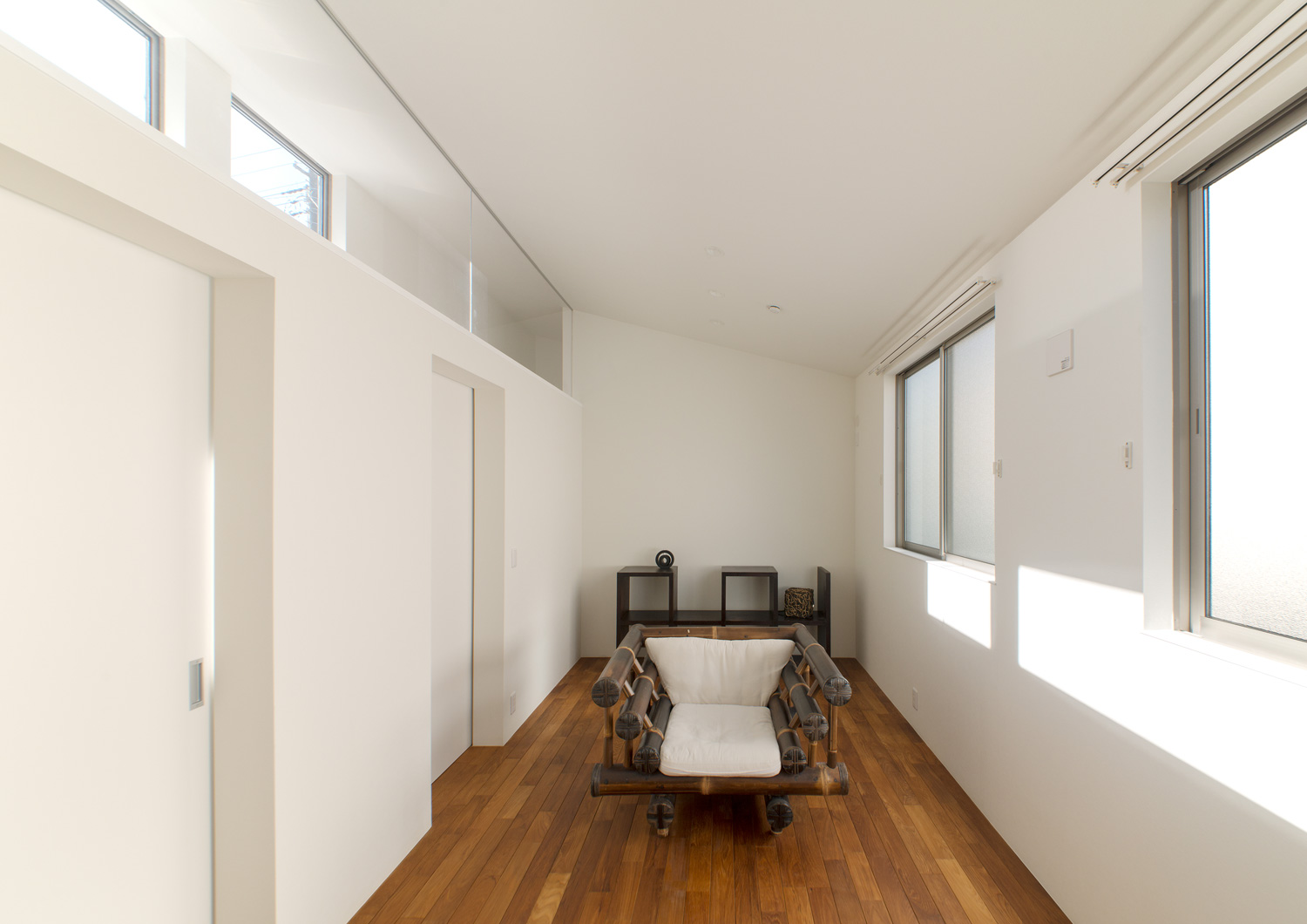 白い壁で、二種類の窓が取り付けられたフローリングの個室・デザイン住宅