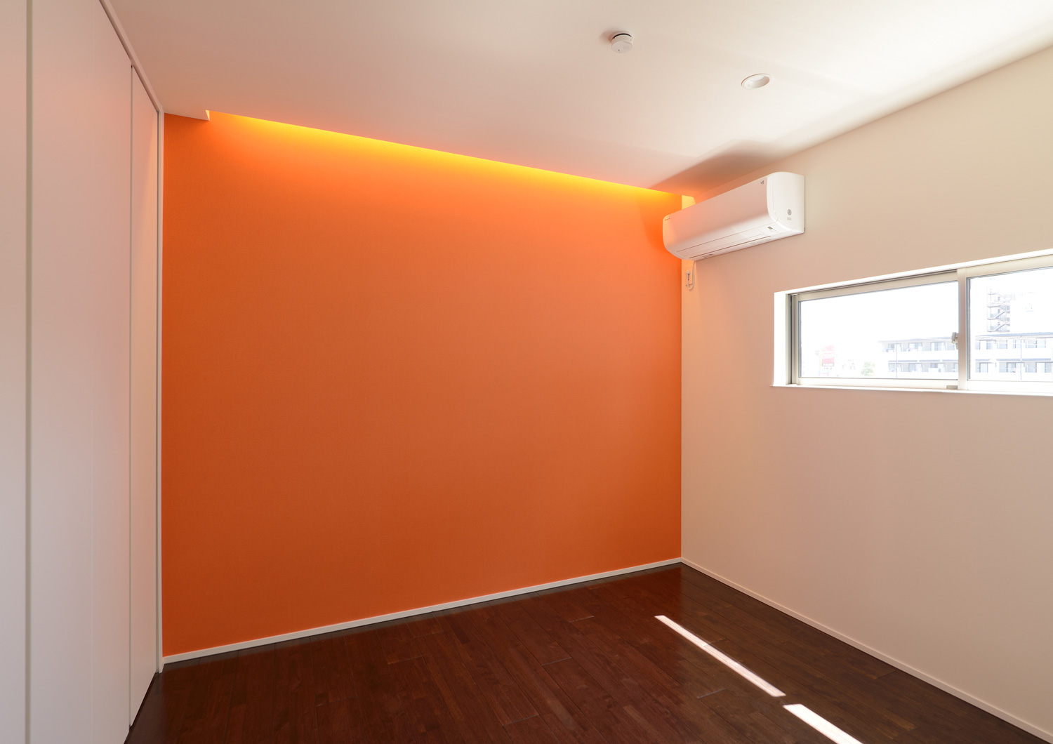 オレンジのアクセントクロスがありスリット窓を取り付けた個室・デザイン住宅