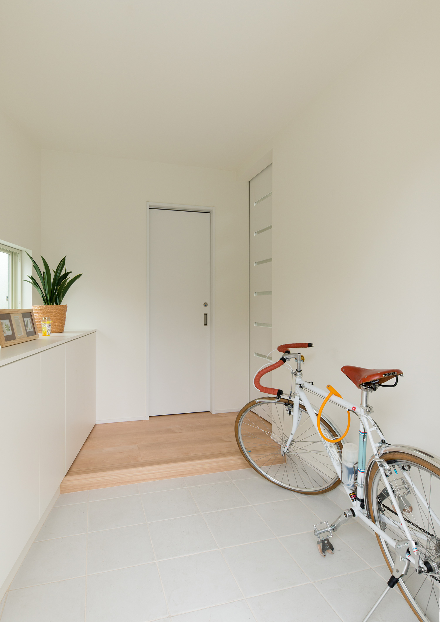 自転車が一台止められた白い壁の玄関・デザイン住宅