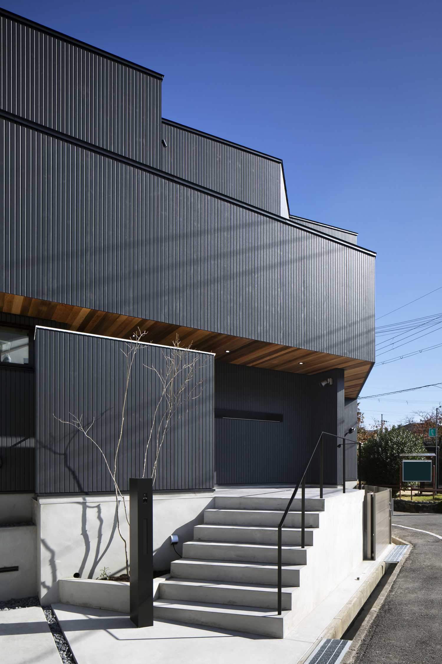 コンクリートの階段のアプローチがある、黒い外壁の住宅・デザイン住宅