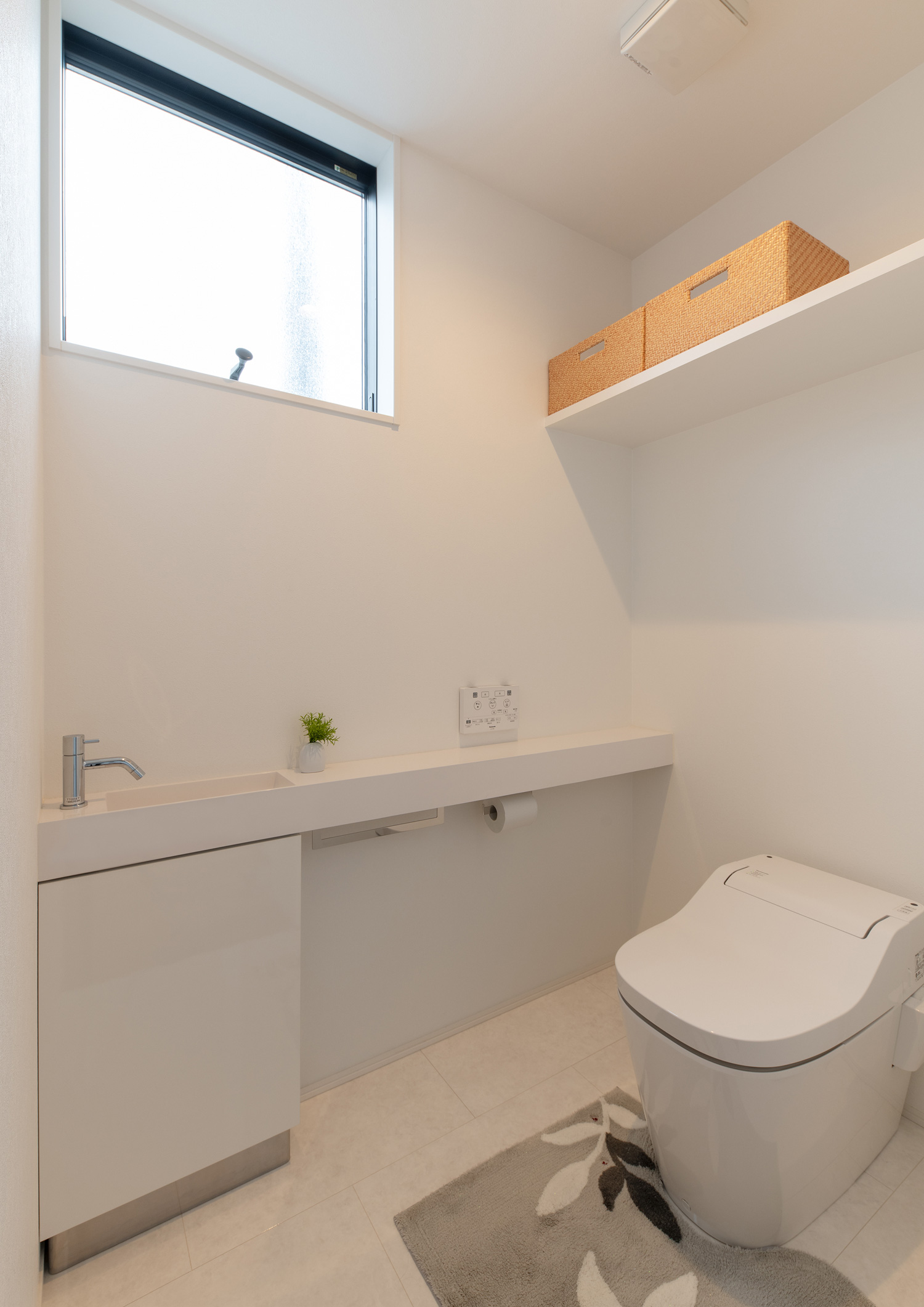 壁付けの棚や薄型手洗いがある白い壁のトイレ・デザイン住宅