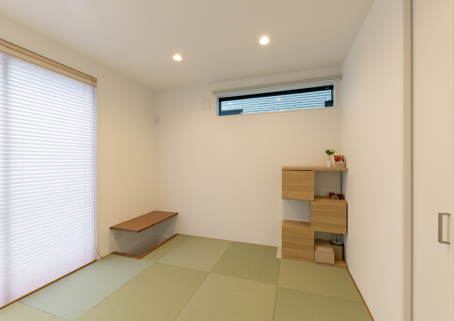 壁付けのデスクや木の棚が設けられた琉球畳の和室・デザイン住宅