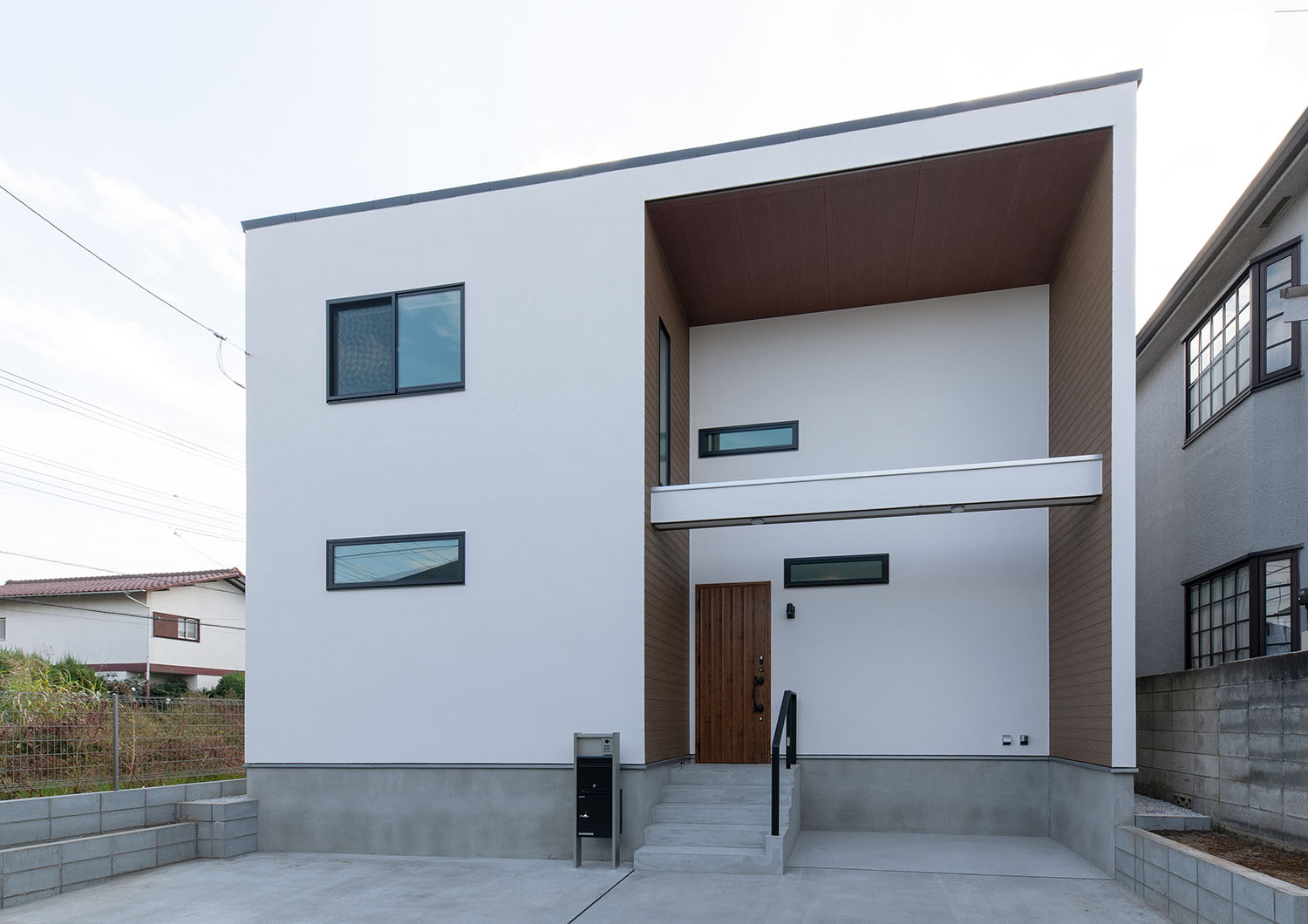 白いキューブ状の外観で、コンクリートの玄関アプローチがある住宅・デザイン住宅
