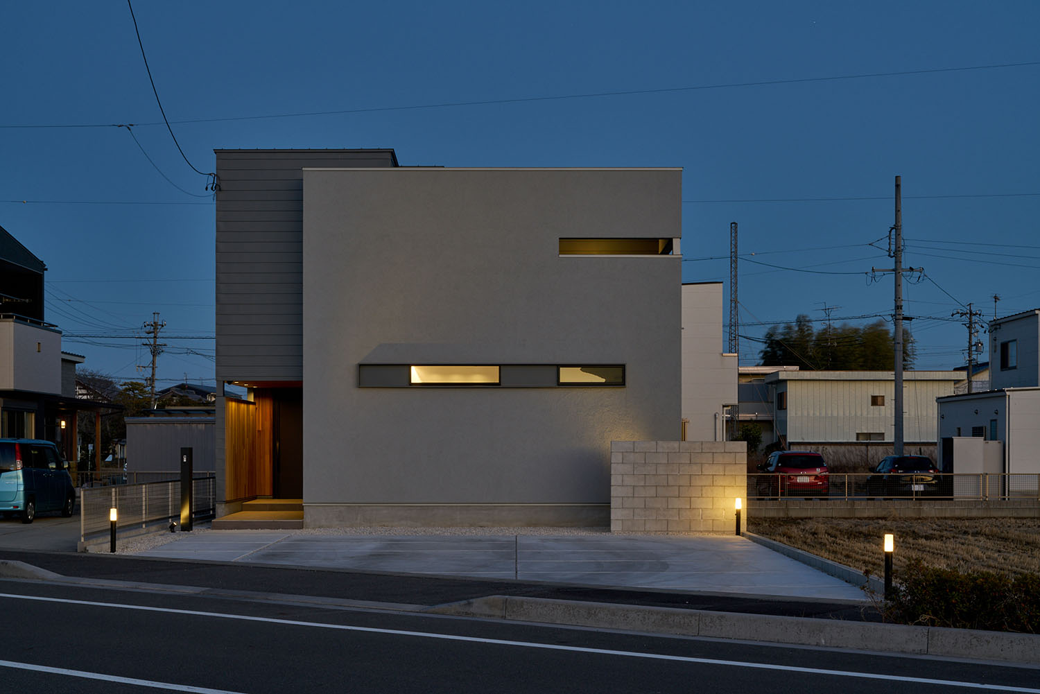 スリット窓からの光や屋外照明によって照らされるキューブ状の外観の住宅・デザイン住宅