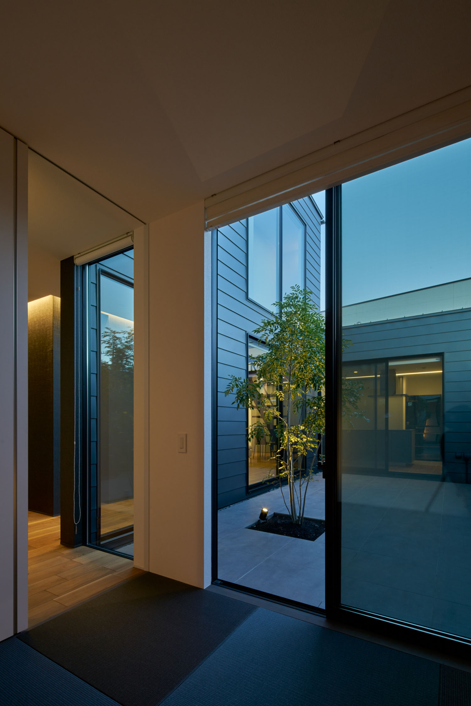 中庭と繋がる大きな窓がある、黒い琉球畳の和室・デザイン住宅