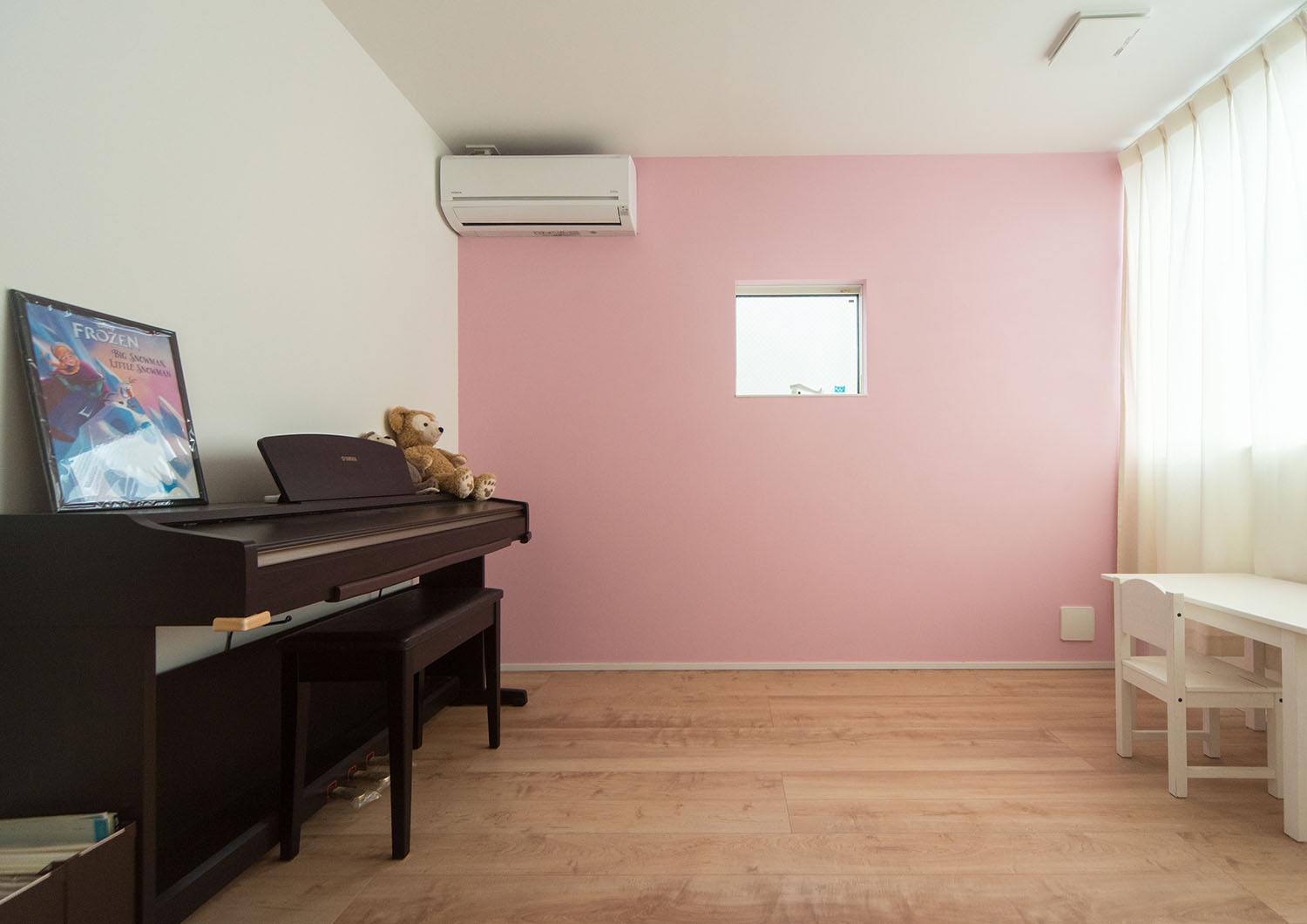 ピアノが置かれた、ピンクのアクセントクロスに小さな窓が取り付けられた部屋・デザイン住宅