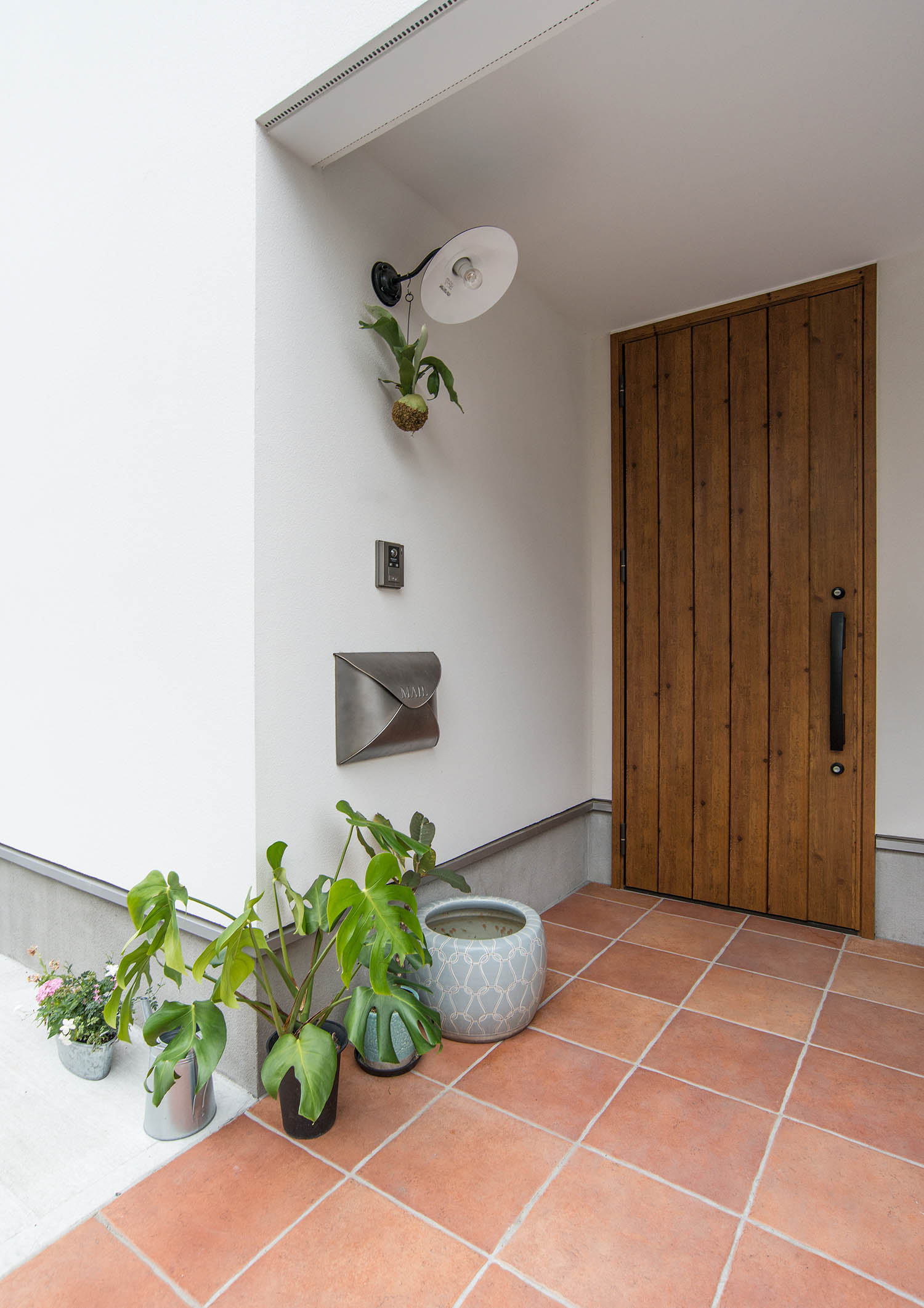 タイル張りの床に観葉植物が置かれている玄関ポーチ・デザイン住宅