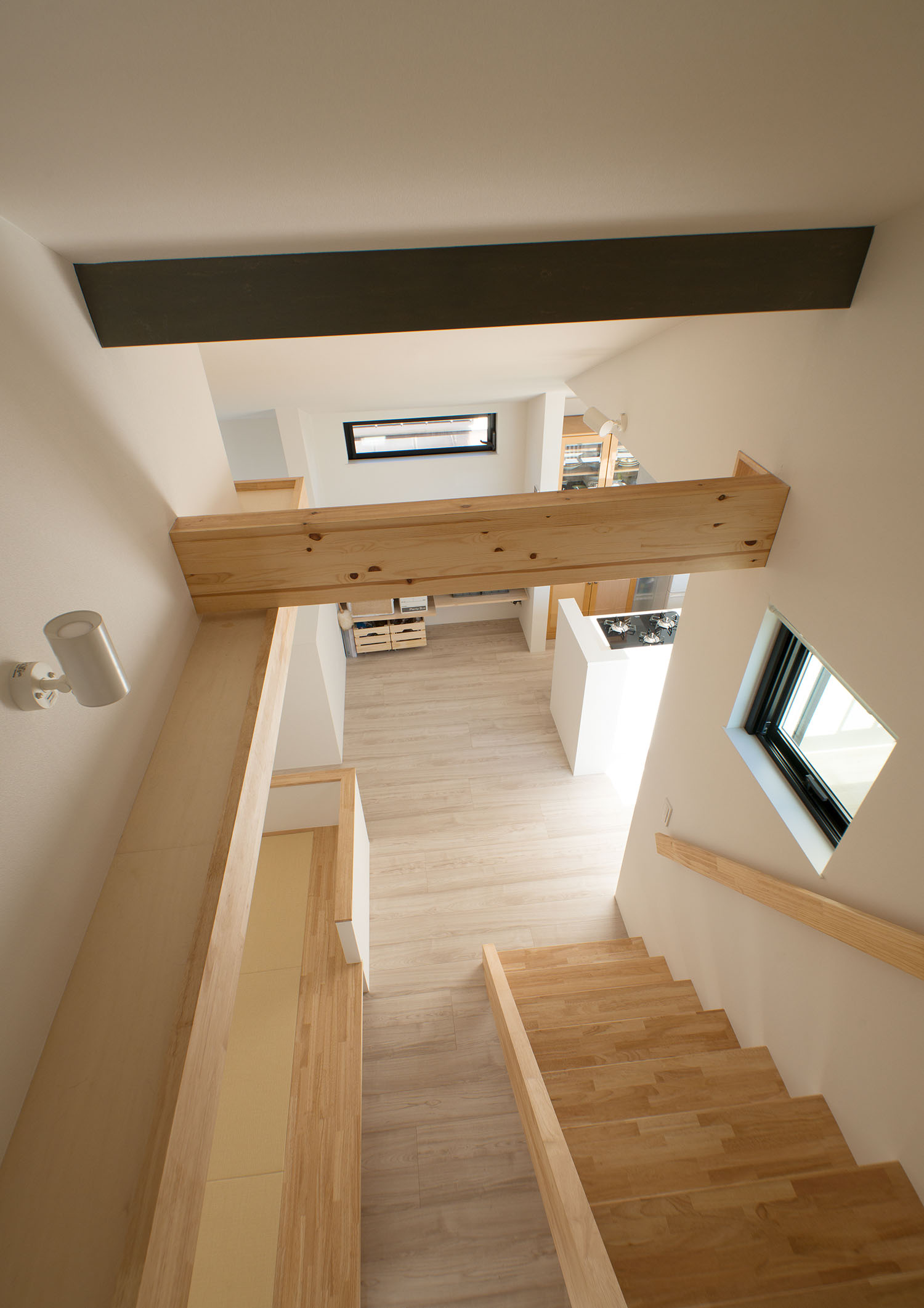 木のスケルトン階段の上部に、木やグレーの梁が設けられている様子・デザイン住宅