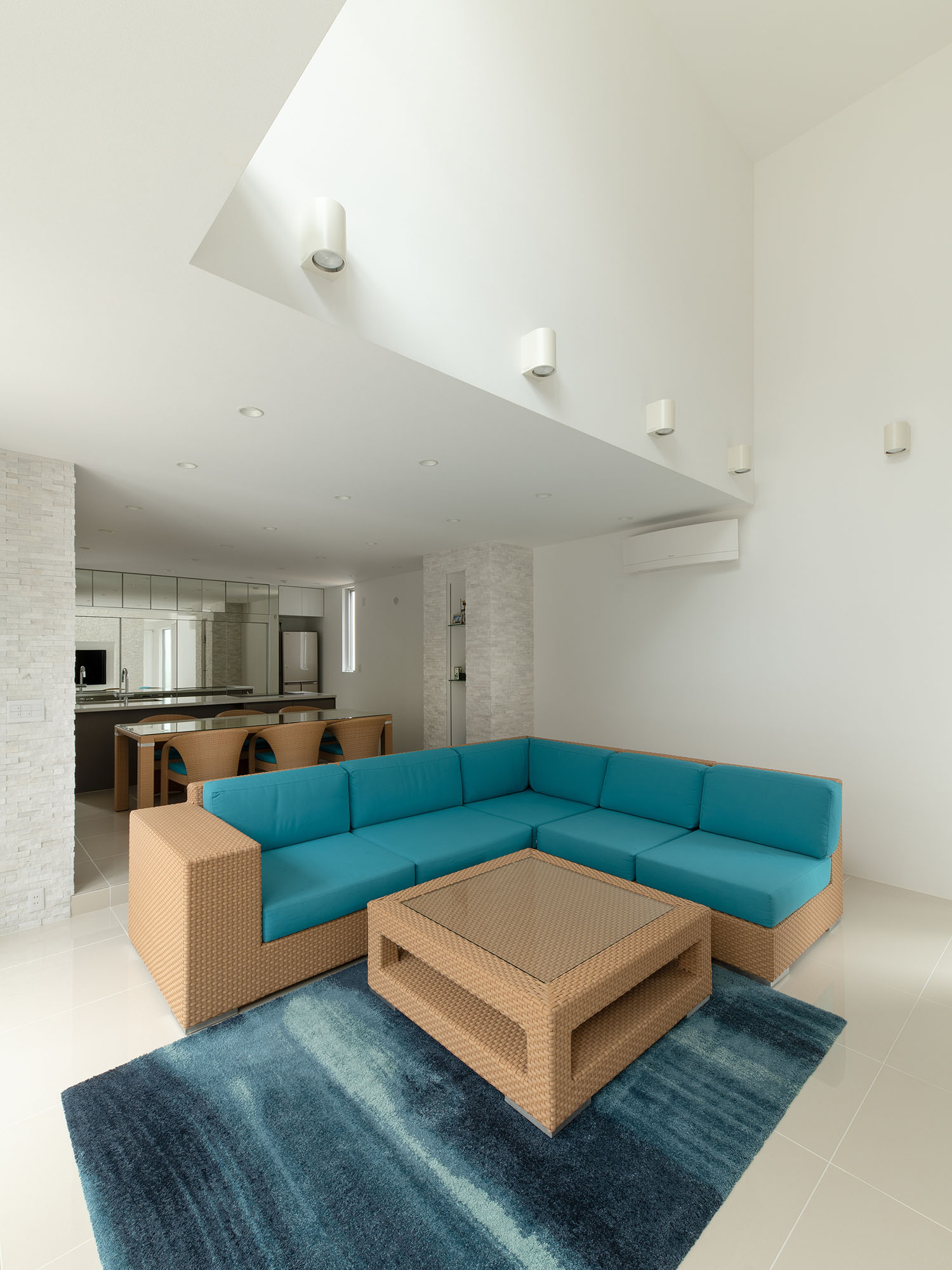 吹き抜けのある、青いソファーを置いたLDK・デザイン住宅