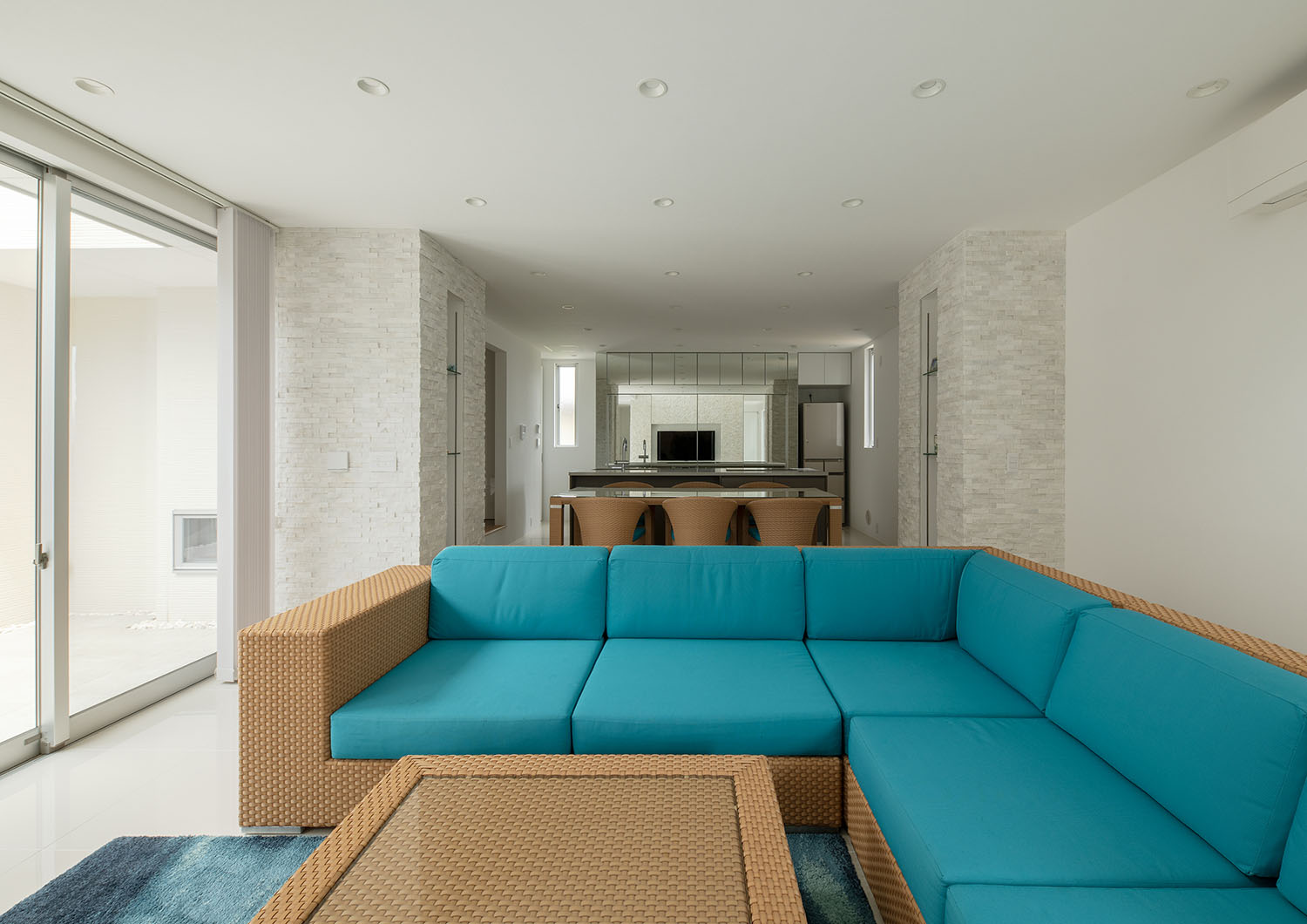 白を基調とした空間に青いソファーがアクセントになっているLDK・デザイン住宅