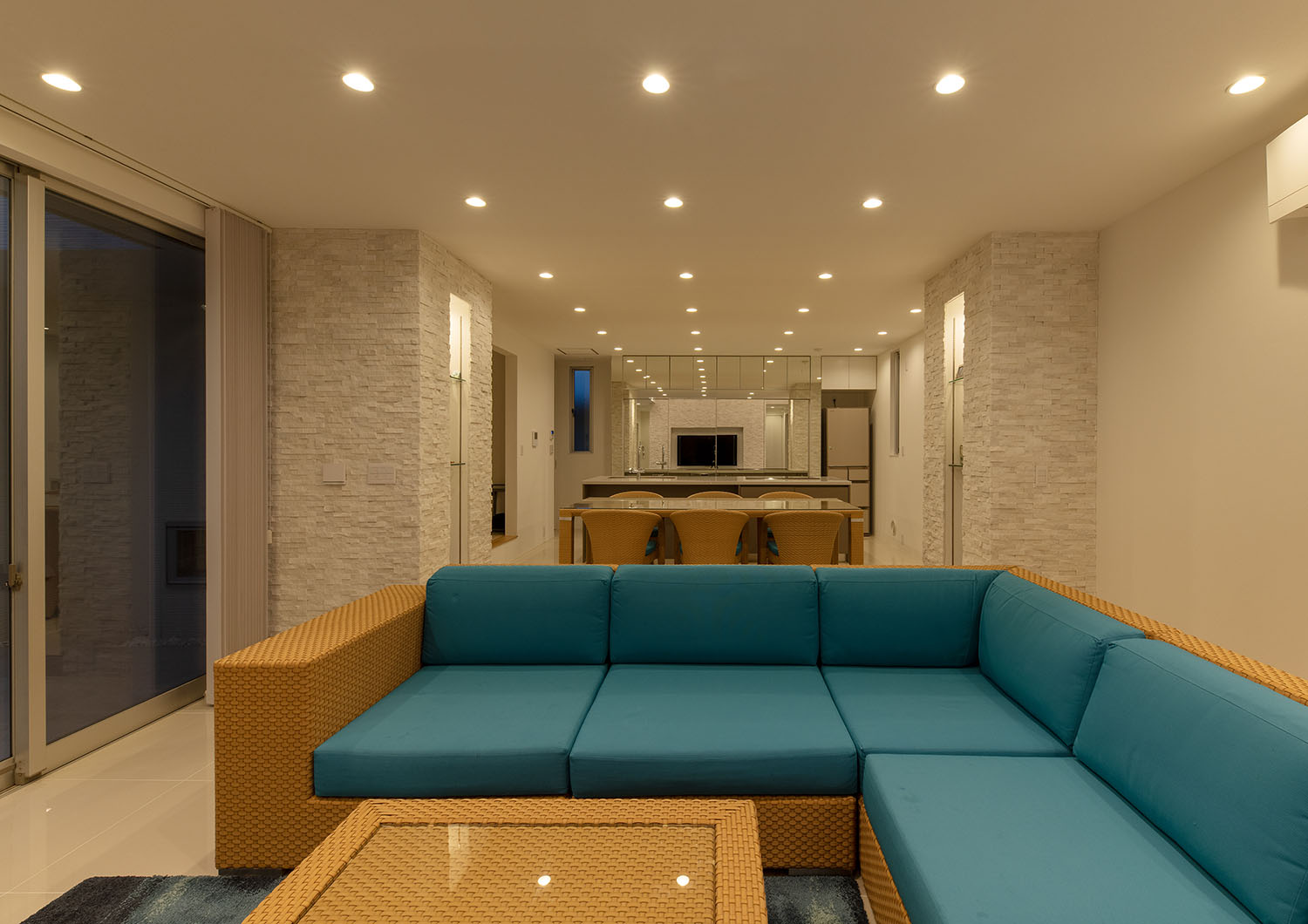 天井に均等にダウンライトが設けられた青いソファーのあるLDK・デザイン住宅