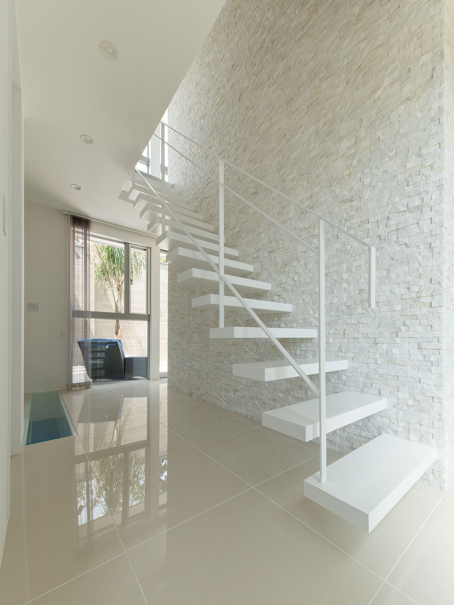 タイル床の空間にある、白い壁に付けられた白いスケルトン階段・デザイン住宅