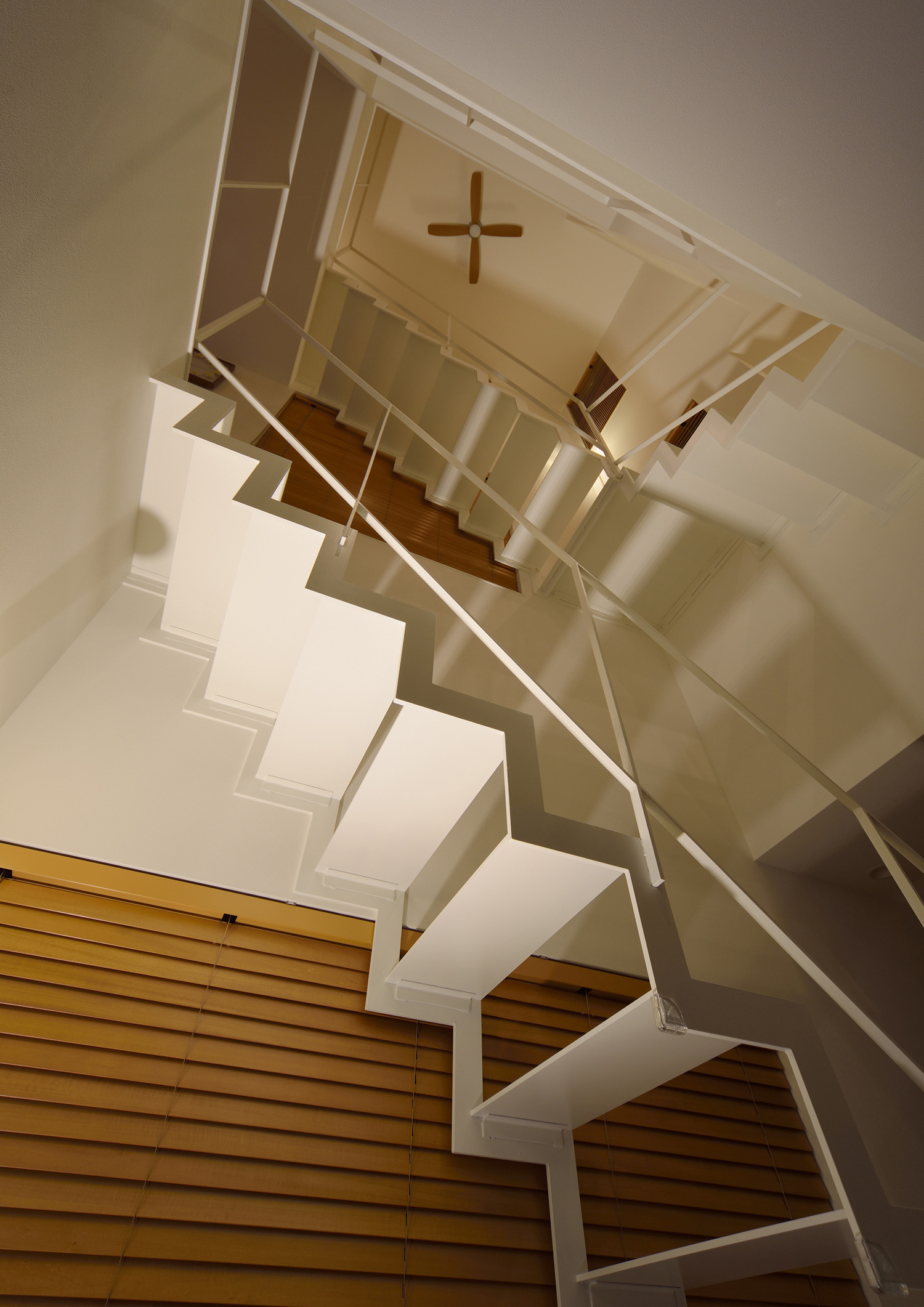 螺旋階段になった白い金属製のスケルトン階段を下から見た様子・デザイン住宅