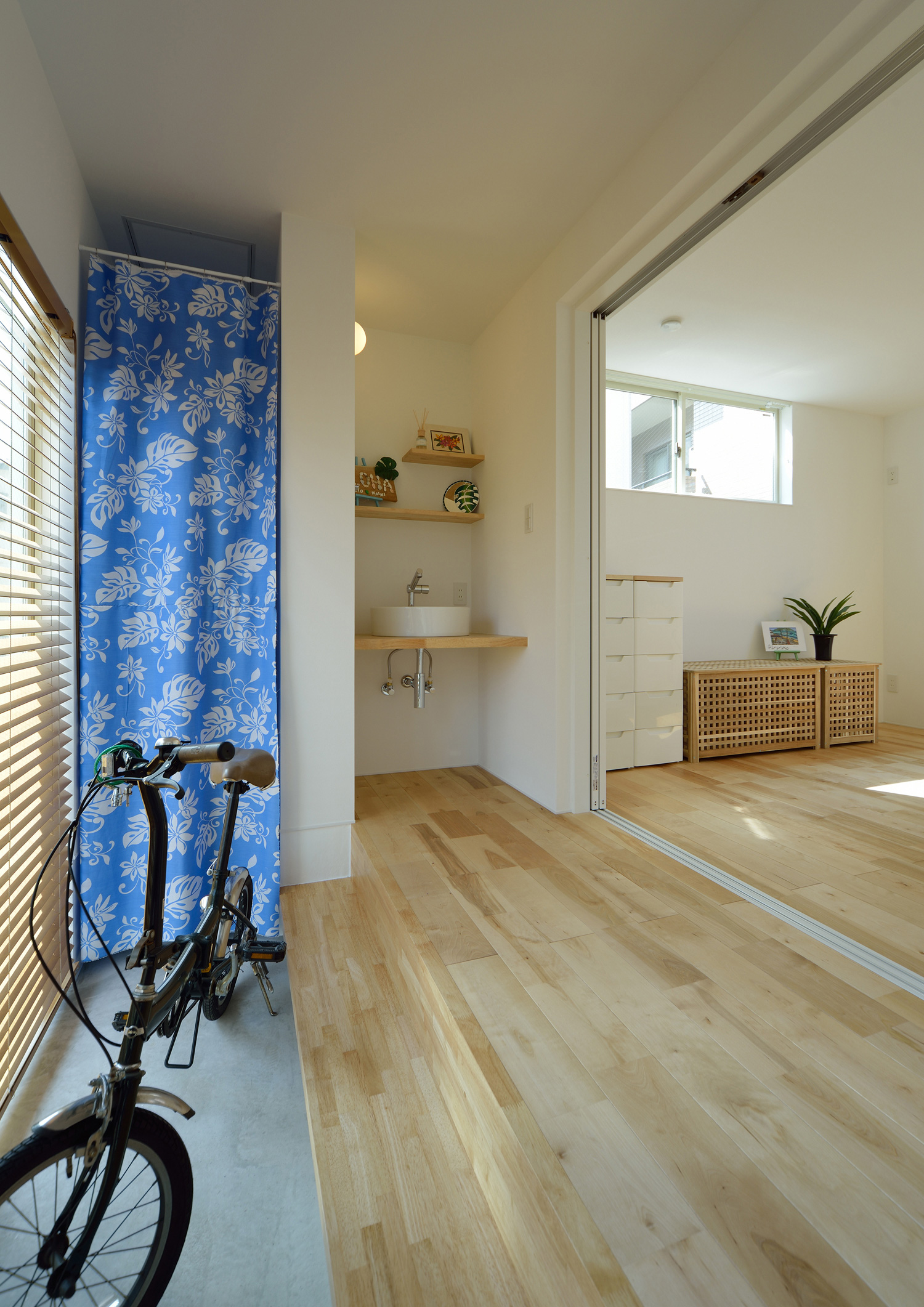 自転車を置いた土間スペースや手洗いカウンターがあるフローリングのフロア・デザイン住宅