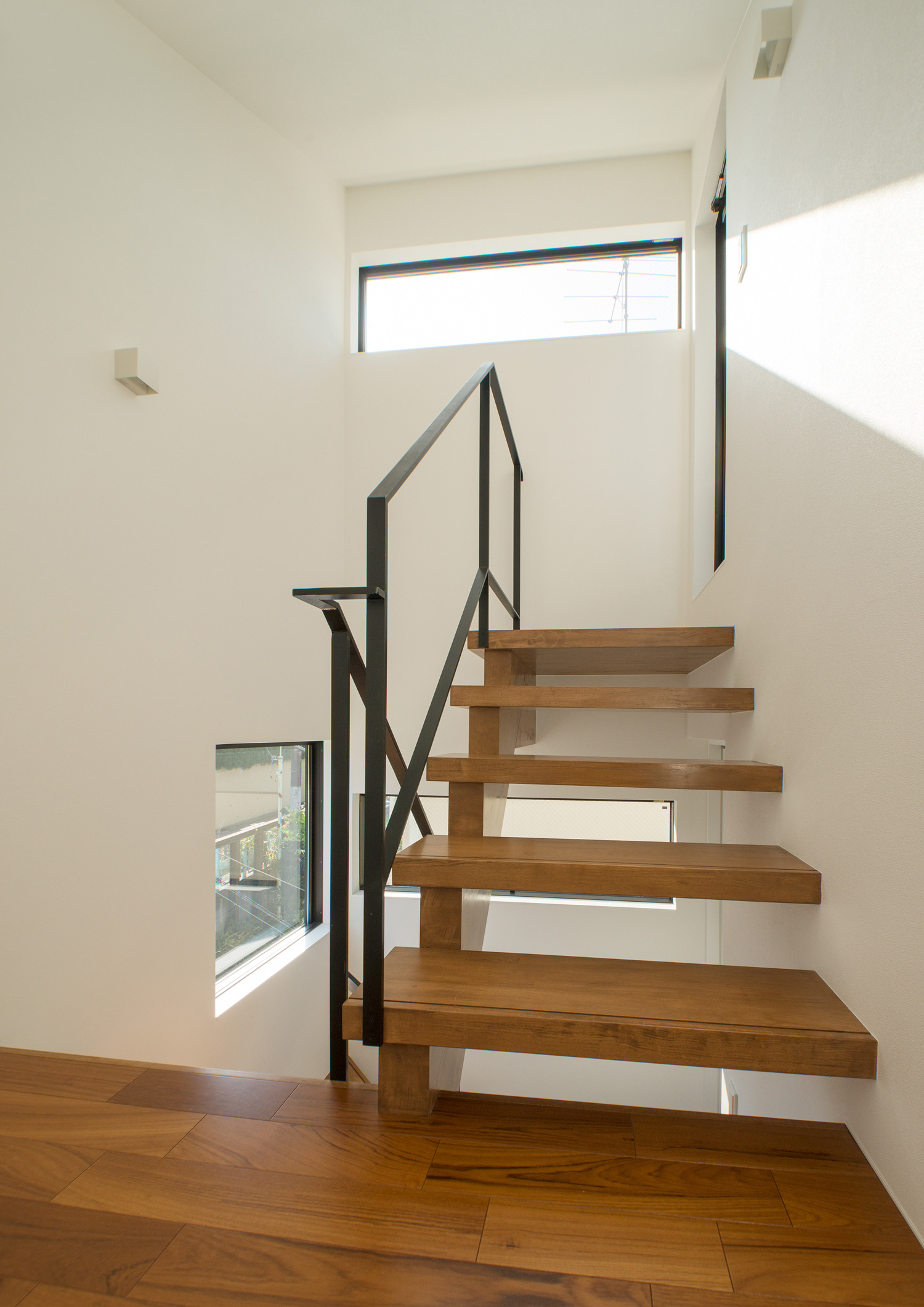 スリット窓から光が入る木のスケルトン階段の階段室・デザイン住宅