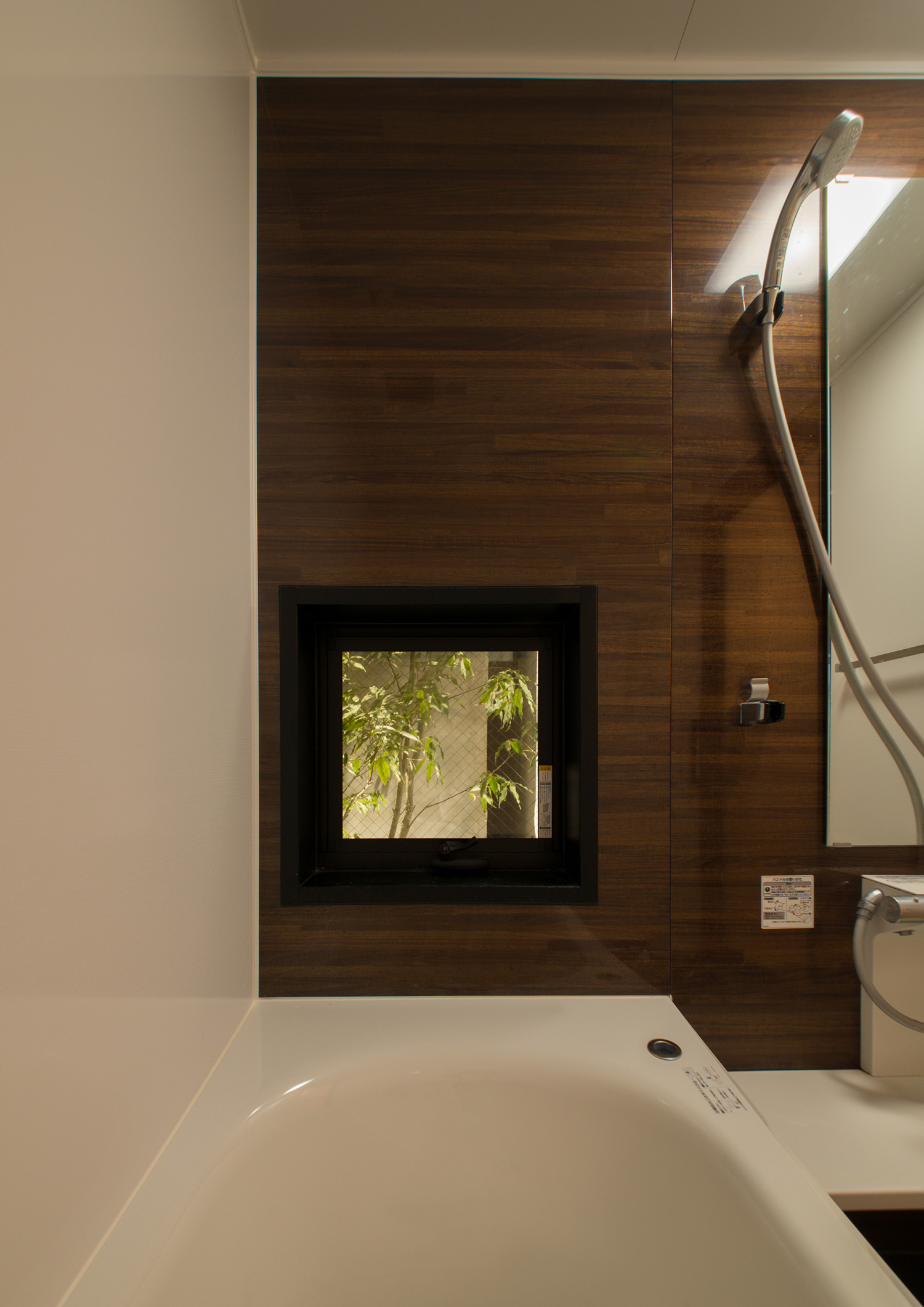 木目のアクセントクロスや植栽が見える小窓がある浴室・デザイン住宅