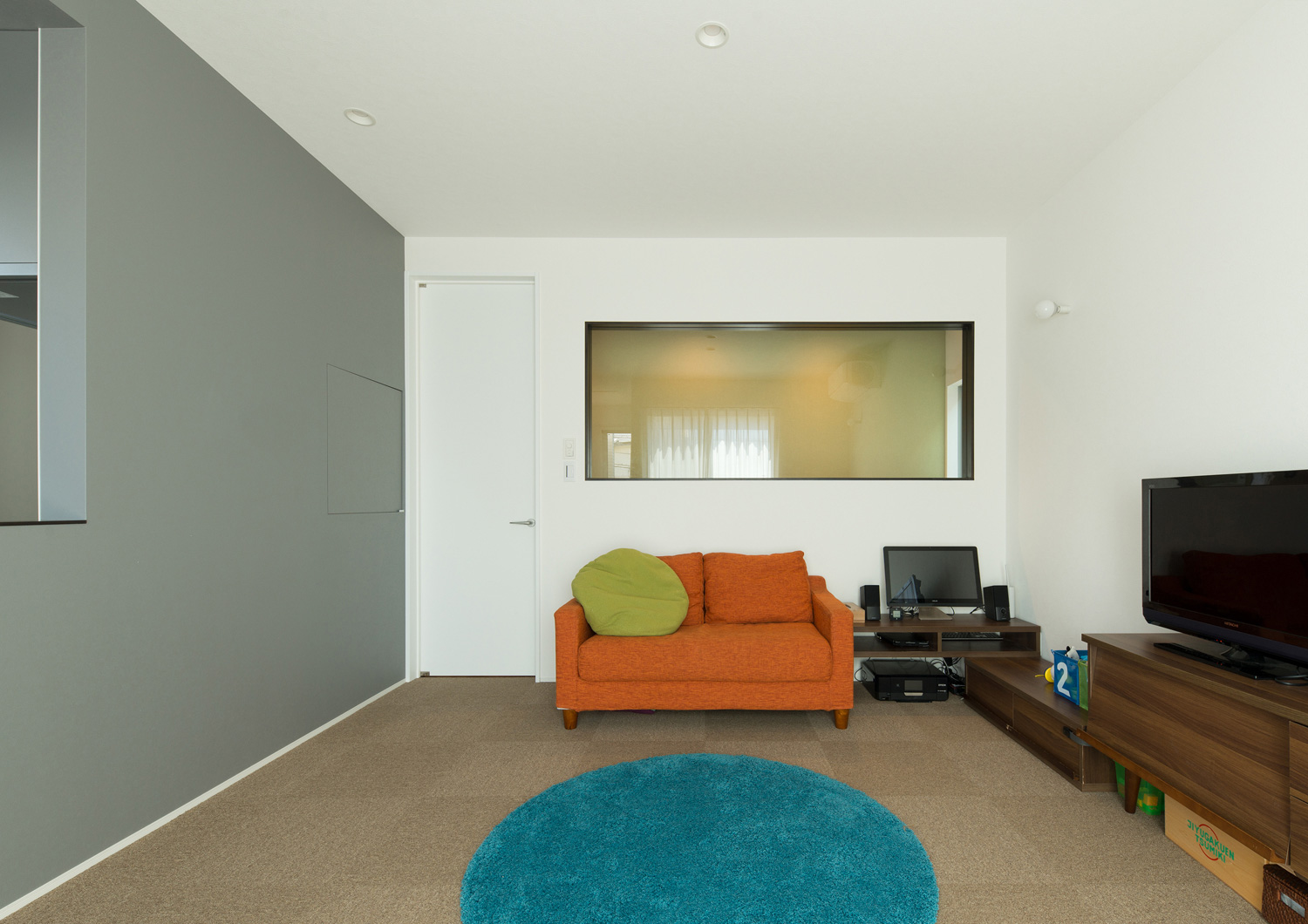 オレンジのソファーや青いラグがあるポップで可愛いLDK・デザイン住宅