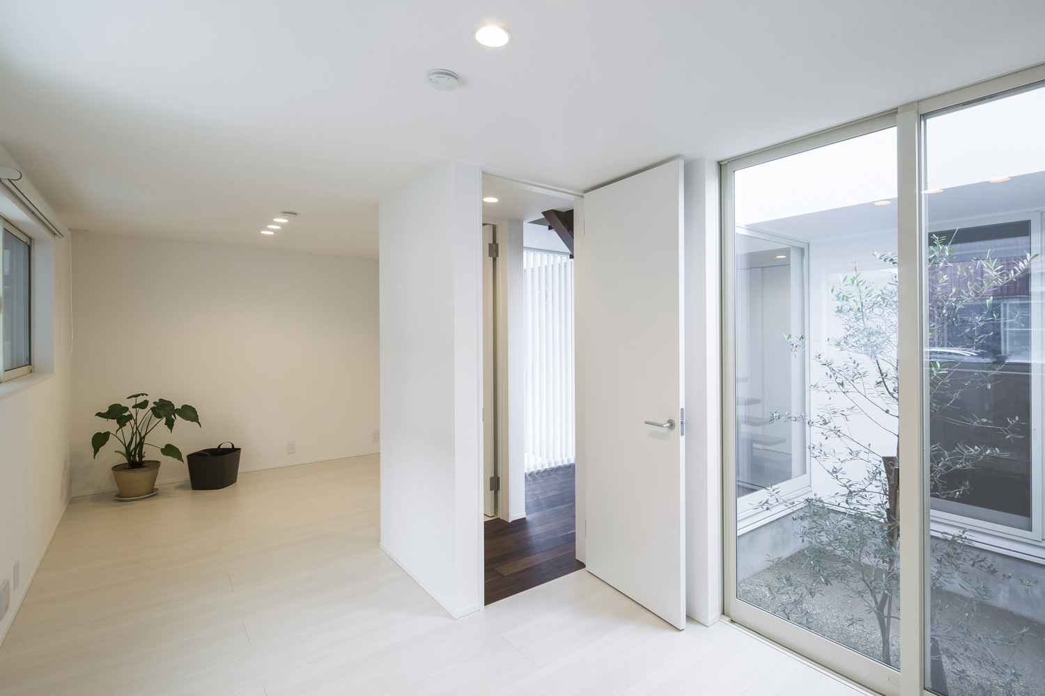 中庭に面した窓がある白い床と壁のシンプルな個室・デザイン住宅