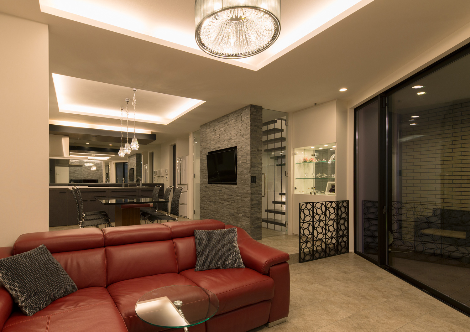 折り上げ天井の間接照明とペンダントライトに照らされる赤いソファーのあるLDK・デザイン住宅