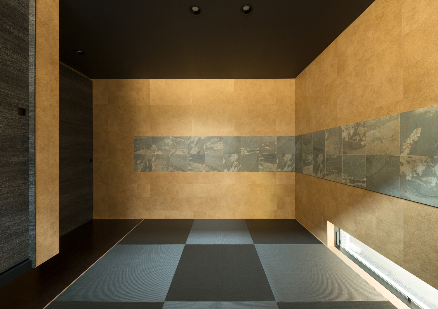 石の壁で、地窓がある黒い琉球畳の和室・デザイン住宅