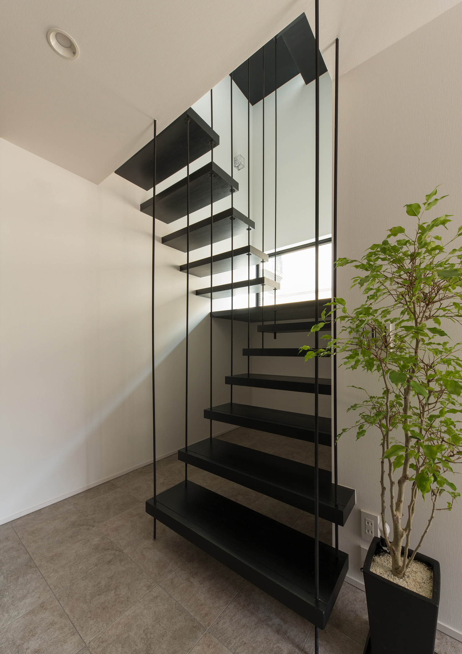 ワイヤーで吊るされているようなデザインの黒いスケルトン階段・デザイン住宅