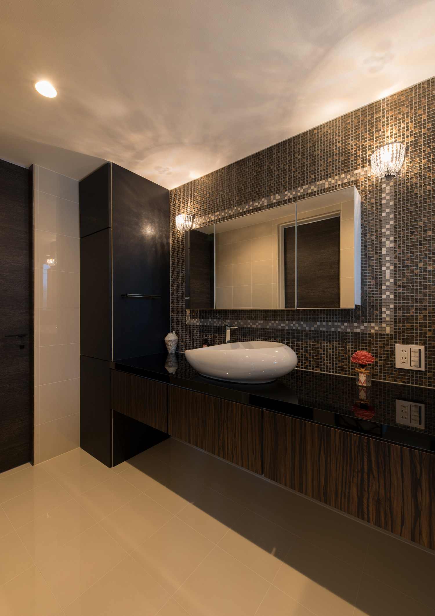 黒いタイルの壁に鏡を取り付けた黒い洗面台の洗面所・デザイン住宅