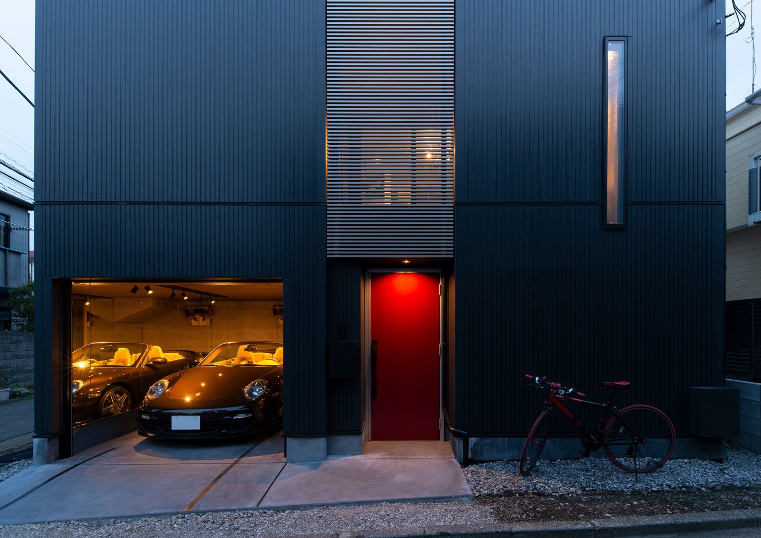 インナーガレージがあり、赤い玄関扉が付いた黒い外壁の住宅・デザイン住宅