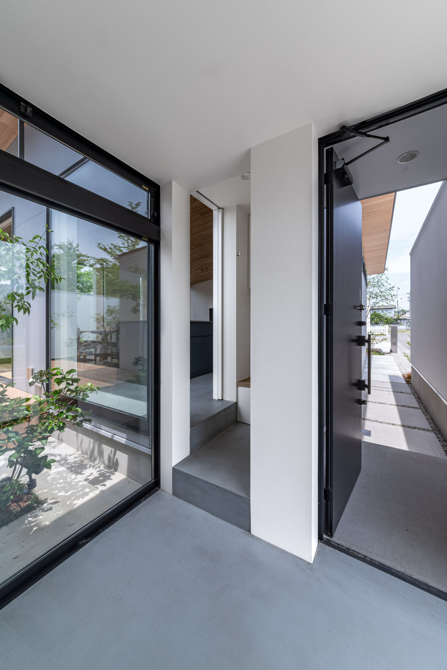 玄関と室内空間をつなぐ、中庭が見えるモルタルの土間・デザイン住宅
