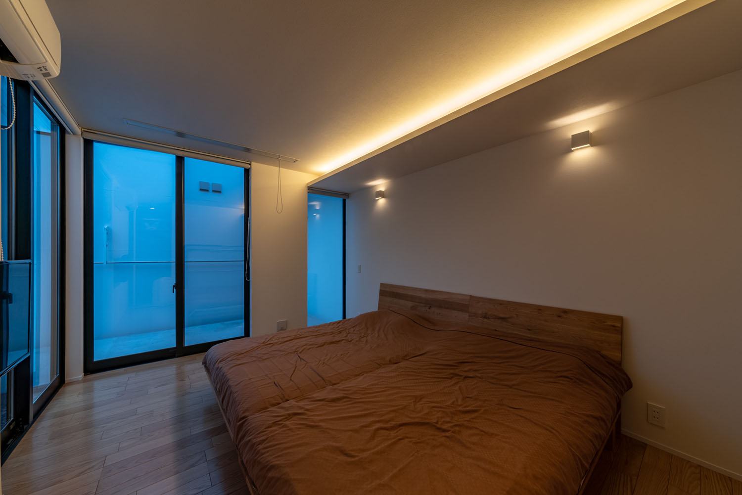 間接照明が取り付けられたブラウンのベッドがある寝室・デザイン住宅