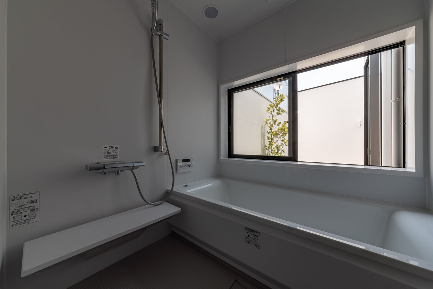 白を基調とした浴室の窓から植栽が見える様子・デザイン住宅