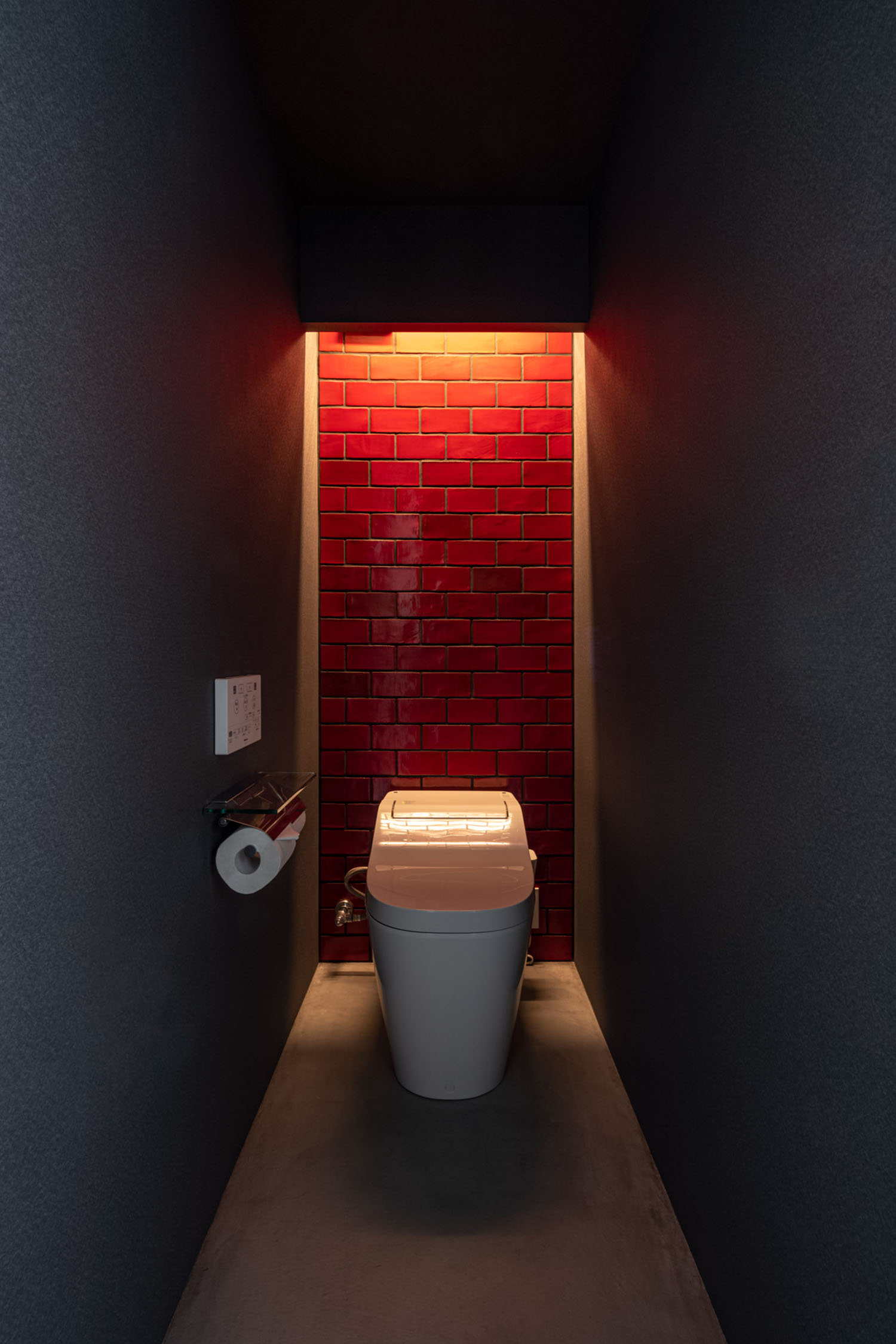 黒い壁に赤いタイルのアクセントウォールがあるトイレ・デザイン住宅
