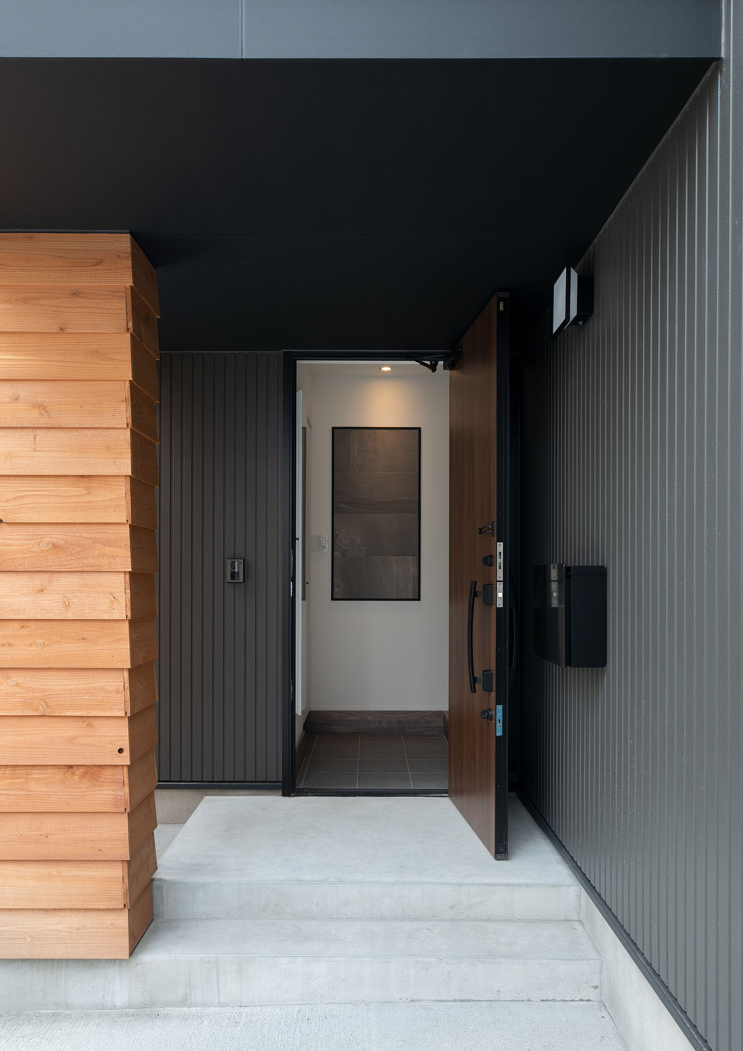 玄関扉を開けた黒を基調とした外観の住宅・デザイン住宅