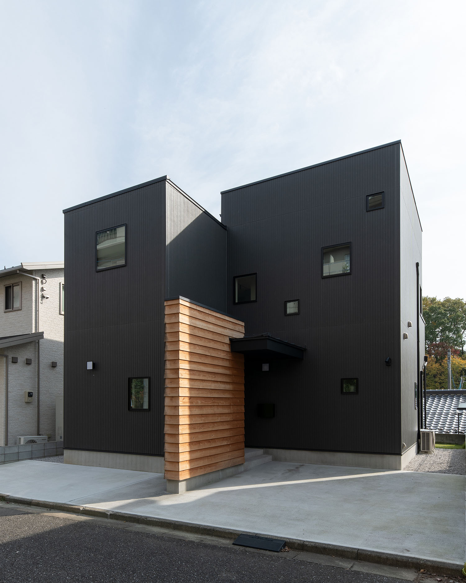 黒を基調とした外観に木材を使用した壁が建てられている住宅・デザイン住宅