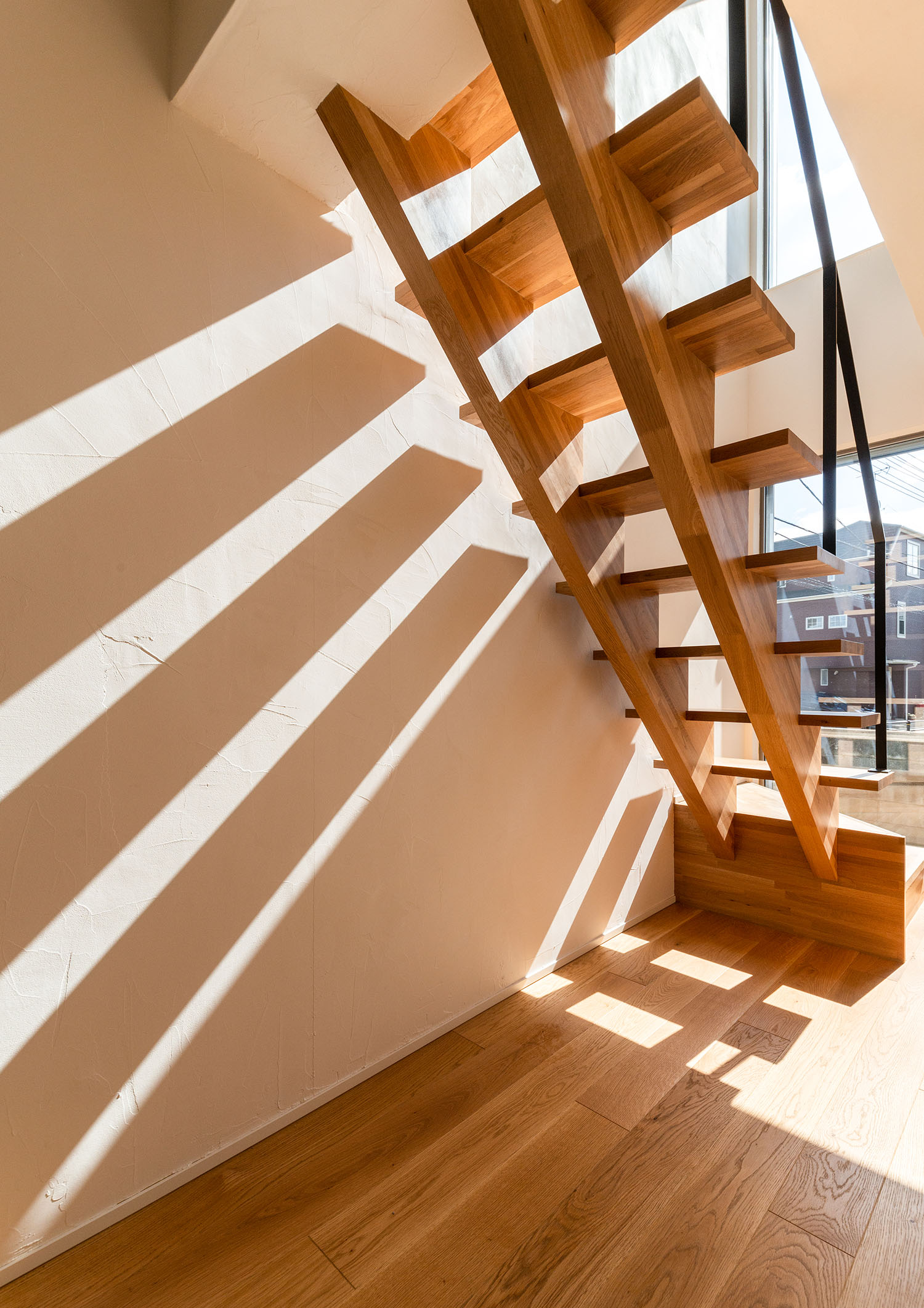窓から自然光が入る木製のスケルトン階段・デザイン住宅
