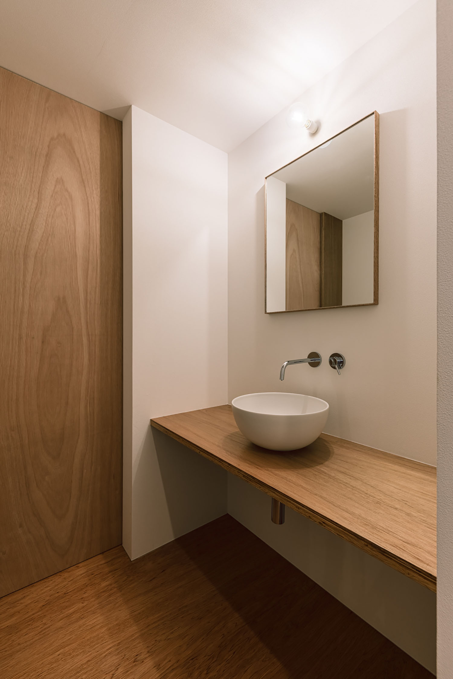 壁付け水栓がある、木材を多用した洗面所・デザイン住宅