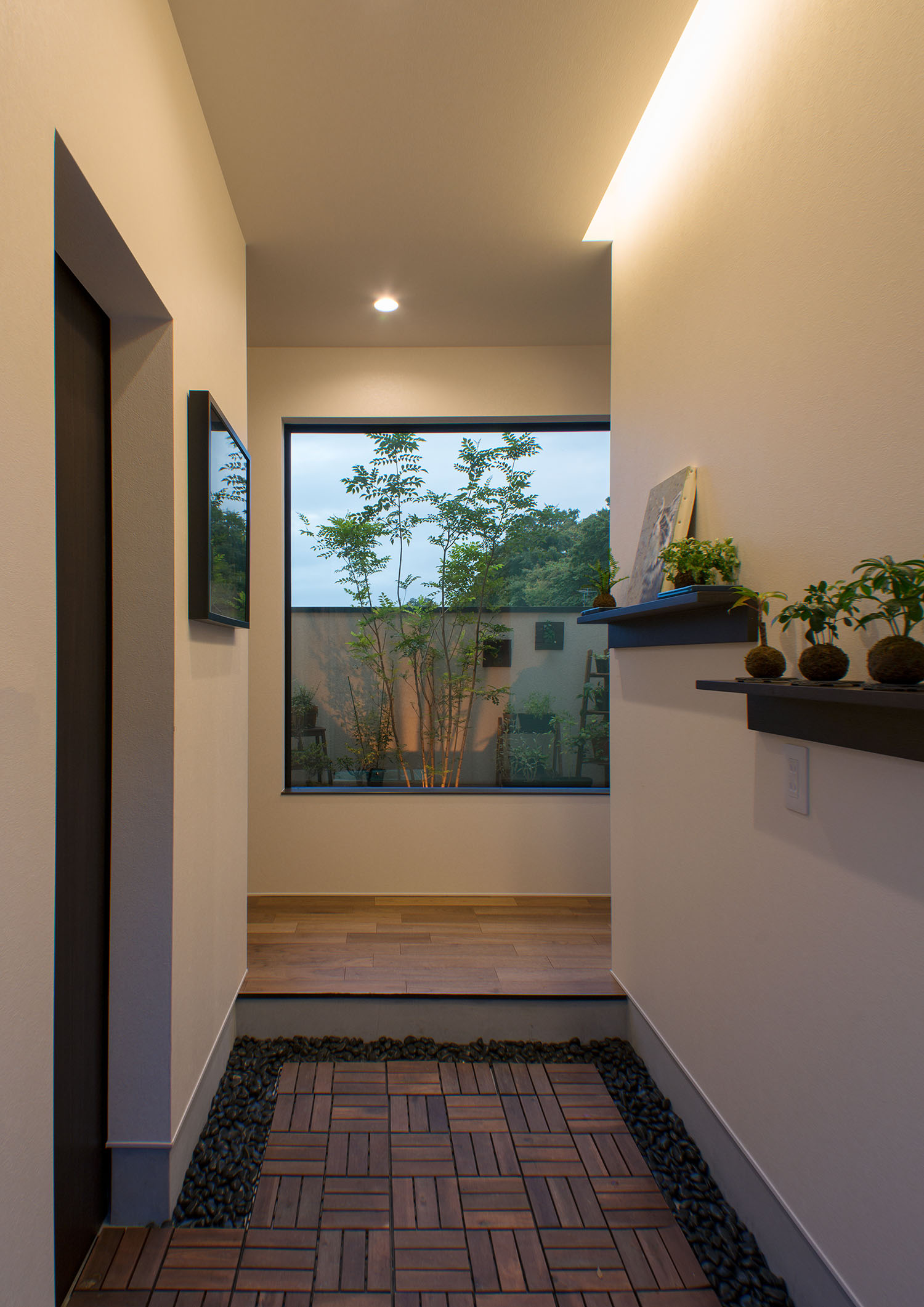 間接照明がついた、正面の窓から植栽が見える玄関・デザイン住宅