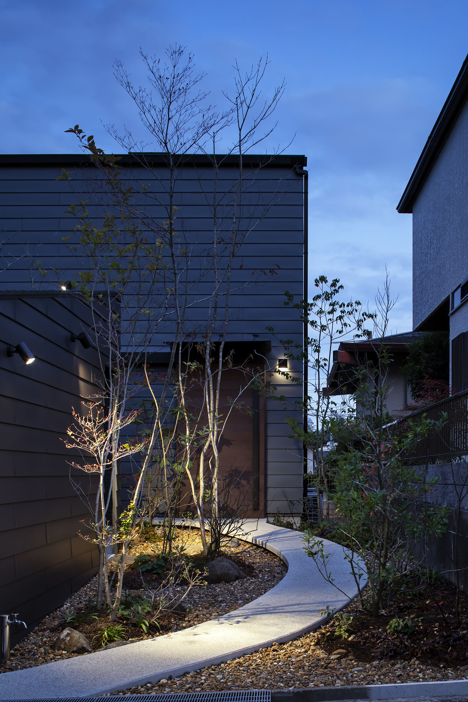 屋外照明によって植栽や玄関が照らされる夜の様子・デザイン住宅