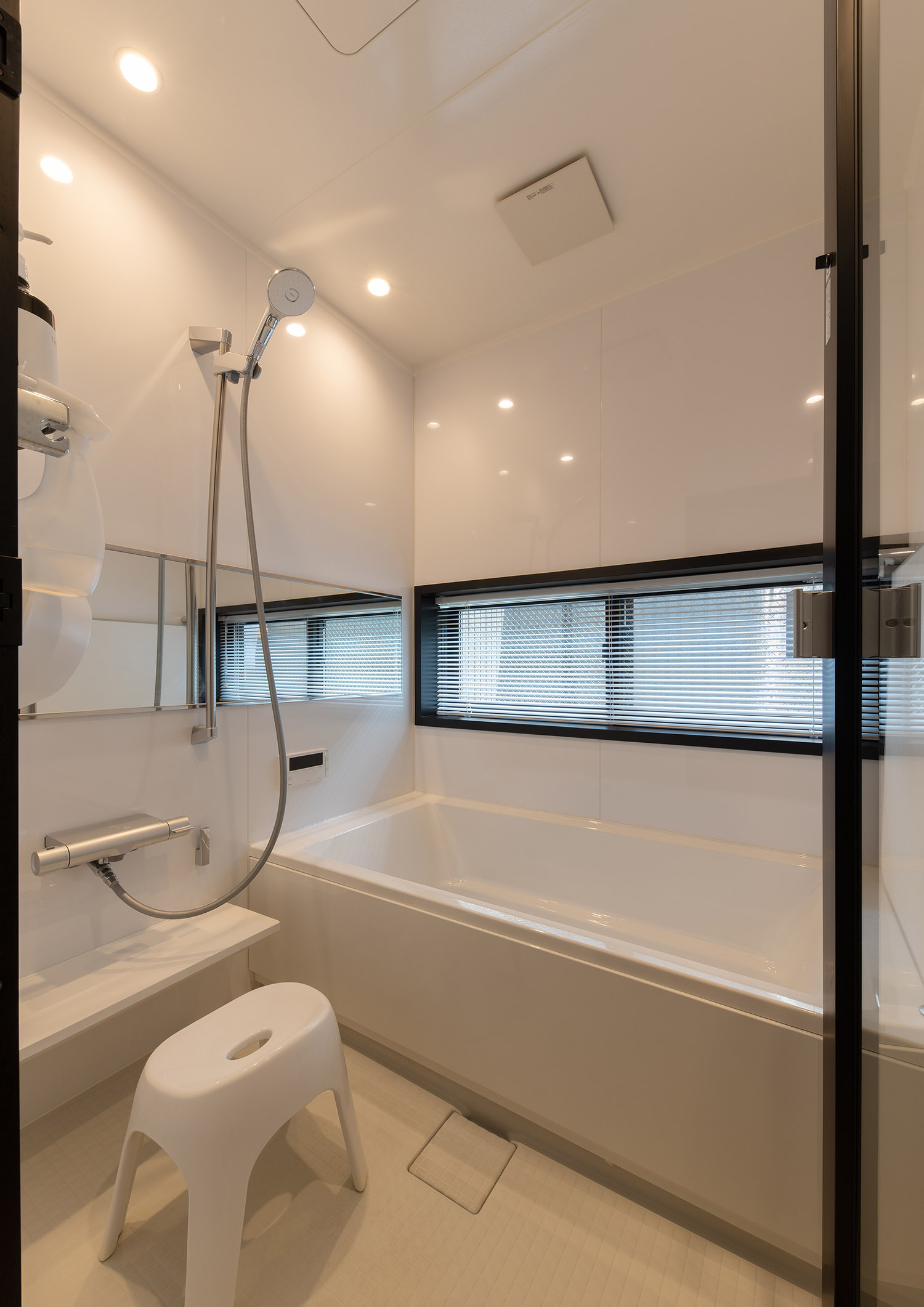 スリット窓を設けた、白を基調とした浴室・フリーダムアーキテクツの事例